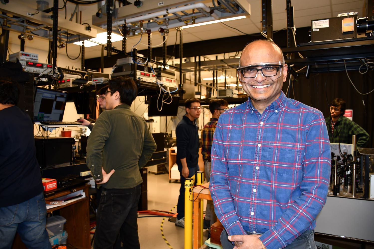 man standing in lab with people working behind him