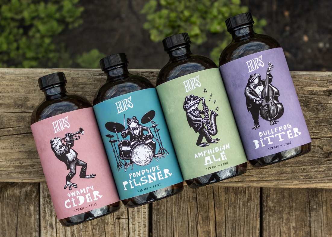 Four beer bottles for Hops brand beer featuring frogs playing musical instruments. 