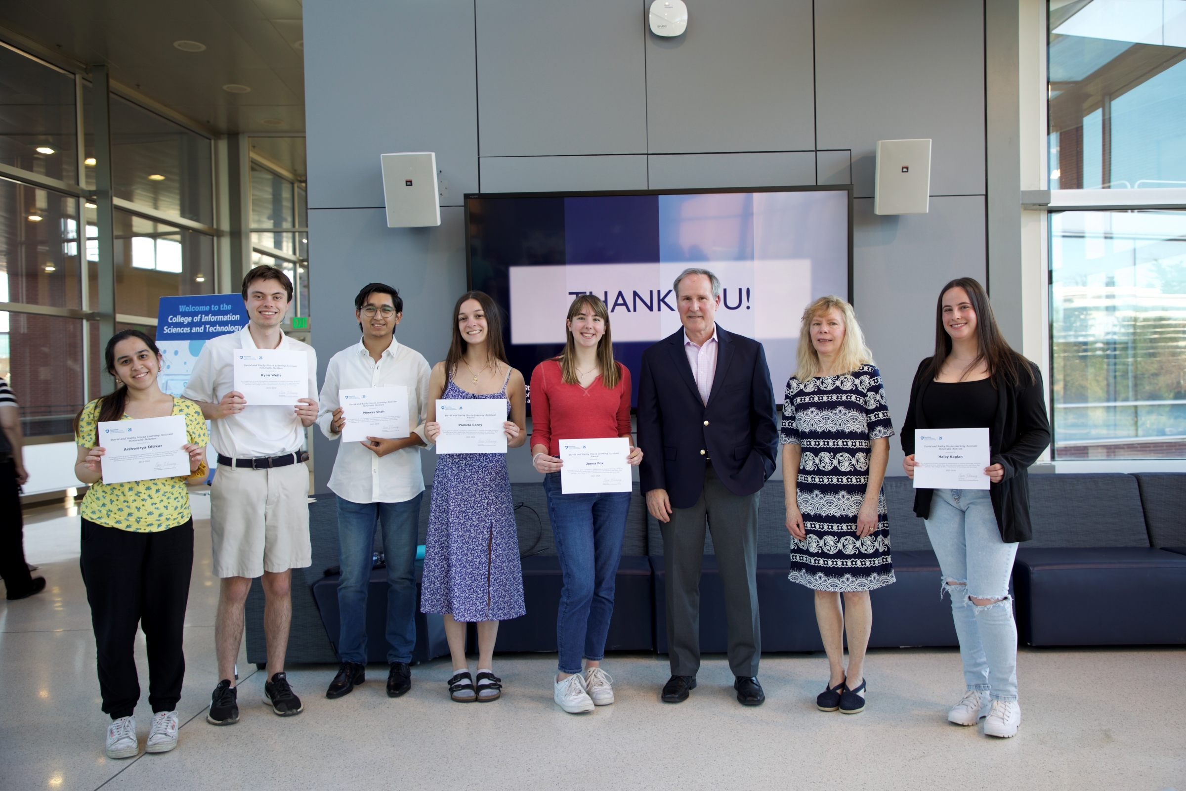 eight people pose with award certificates