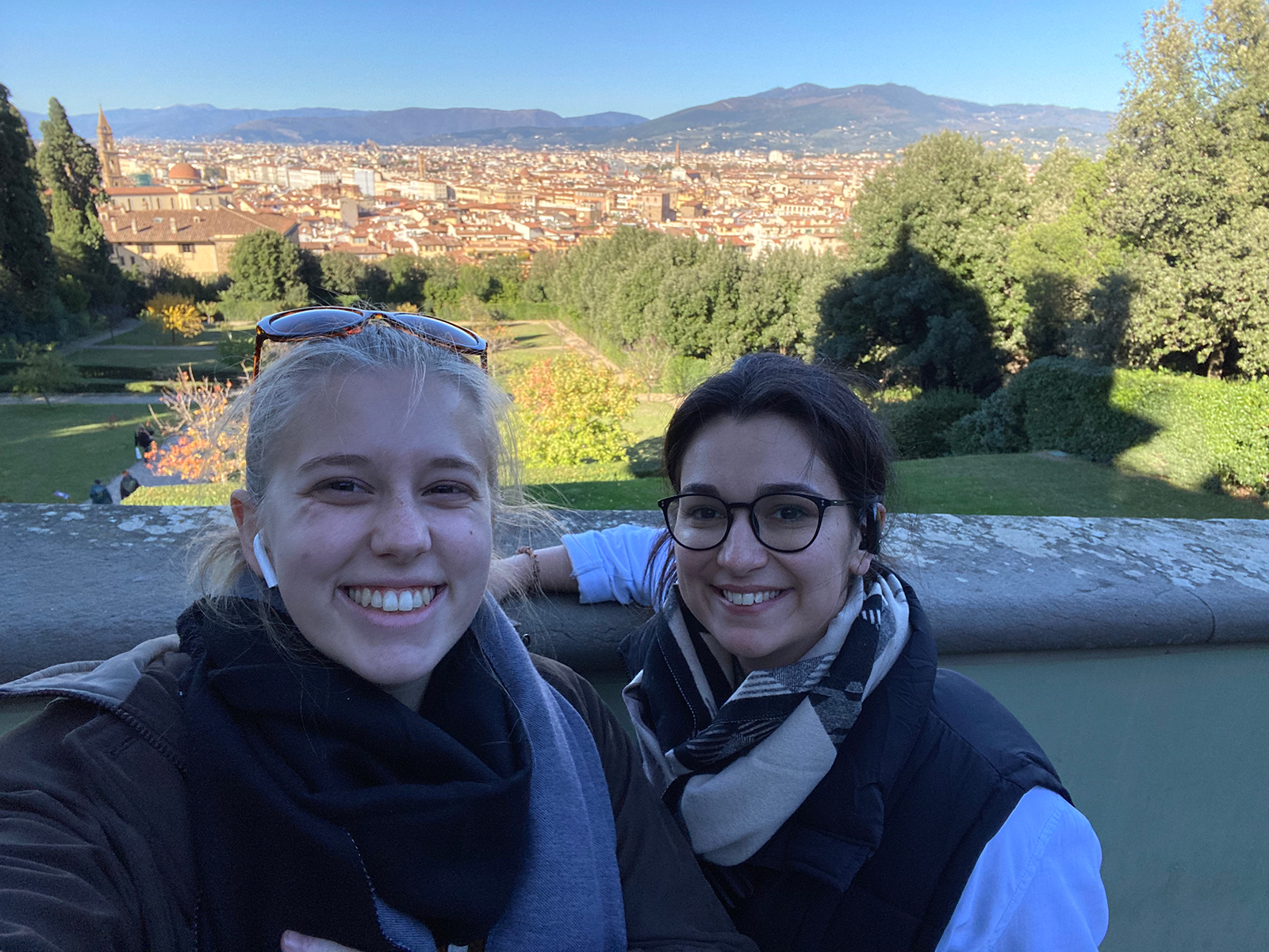 Two women standing in front of a scenic background.