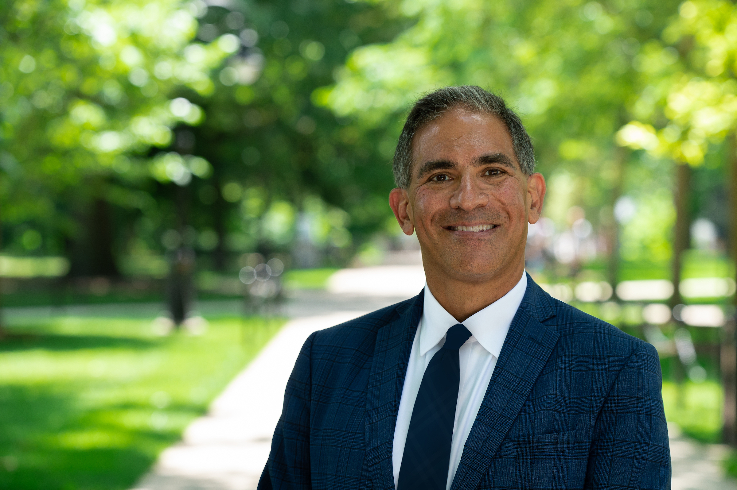 Justin Schwartz smiles and stands outside with green trees in the background.