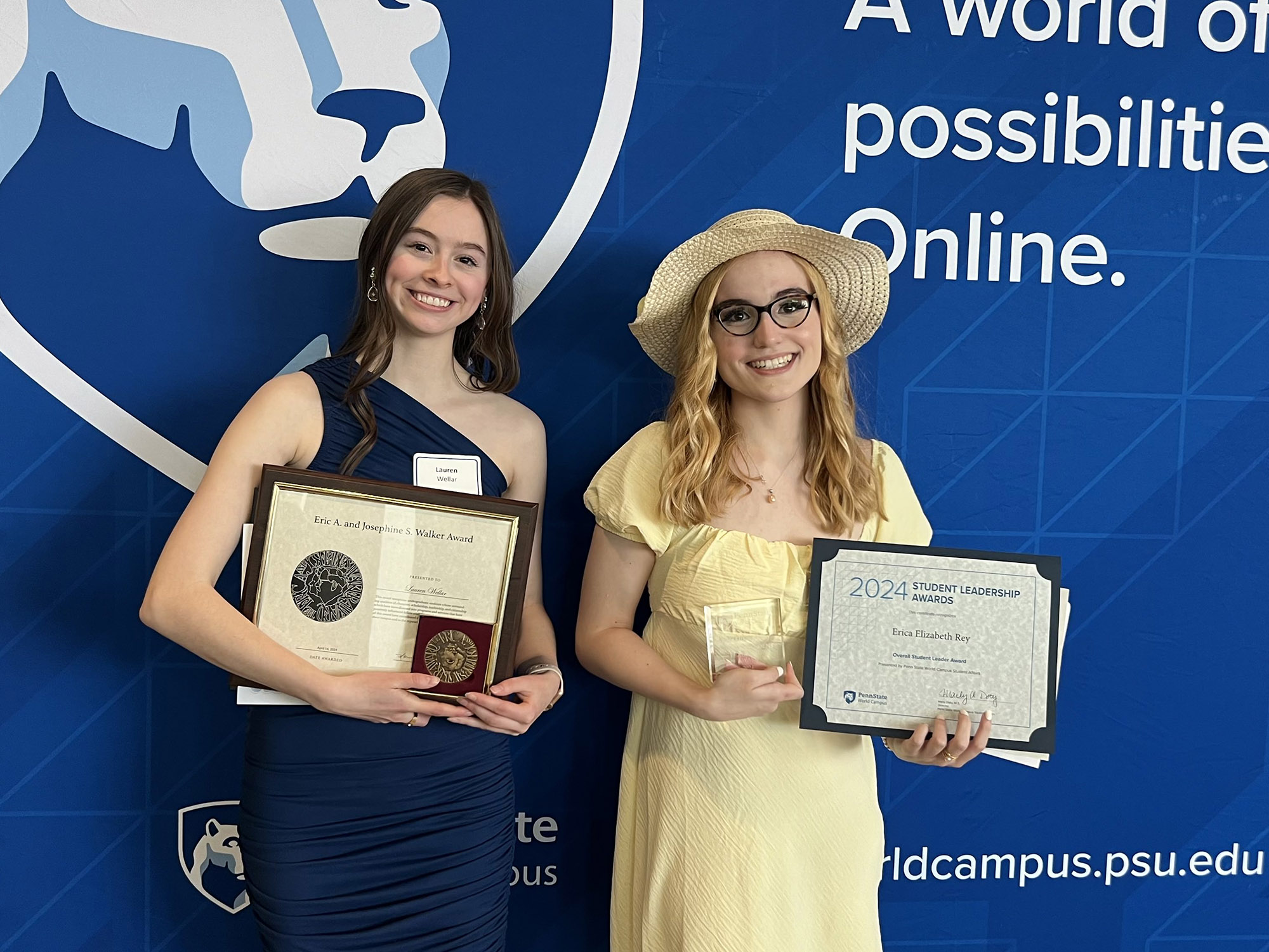 Two women hold plaques for their awards