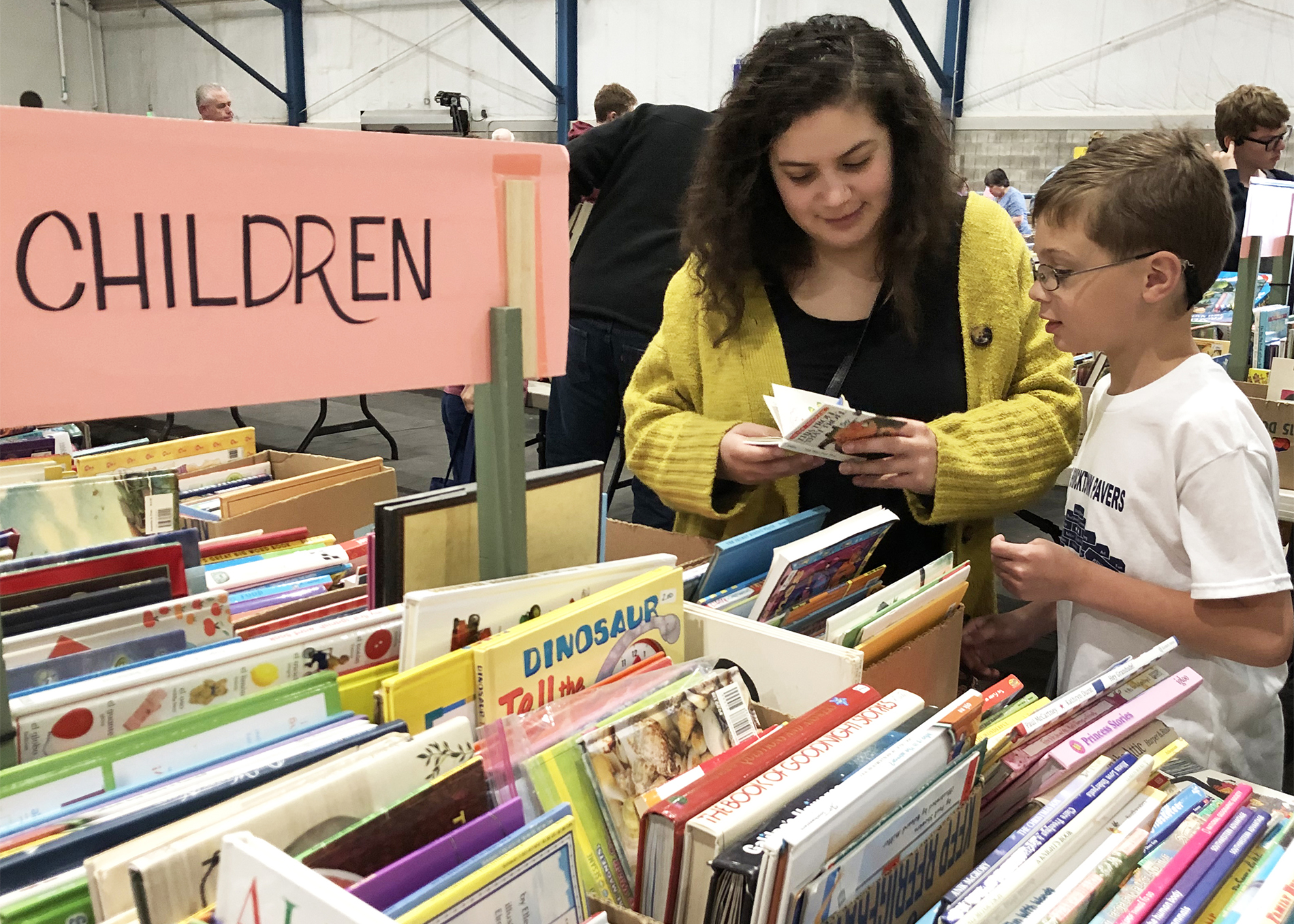 A mother and son browse books in the children's section of the AAUW book sale.