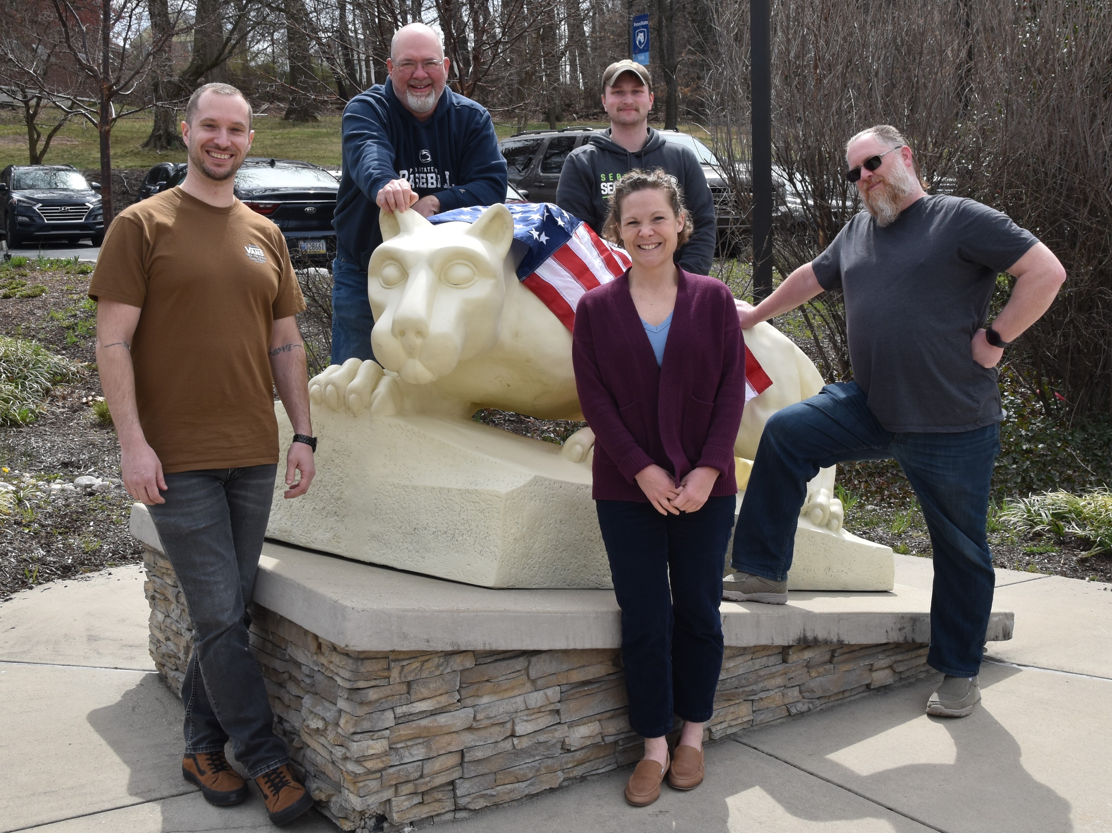 Four men and a woman standing around the lion shrine statue.