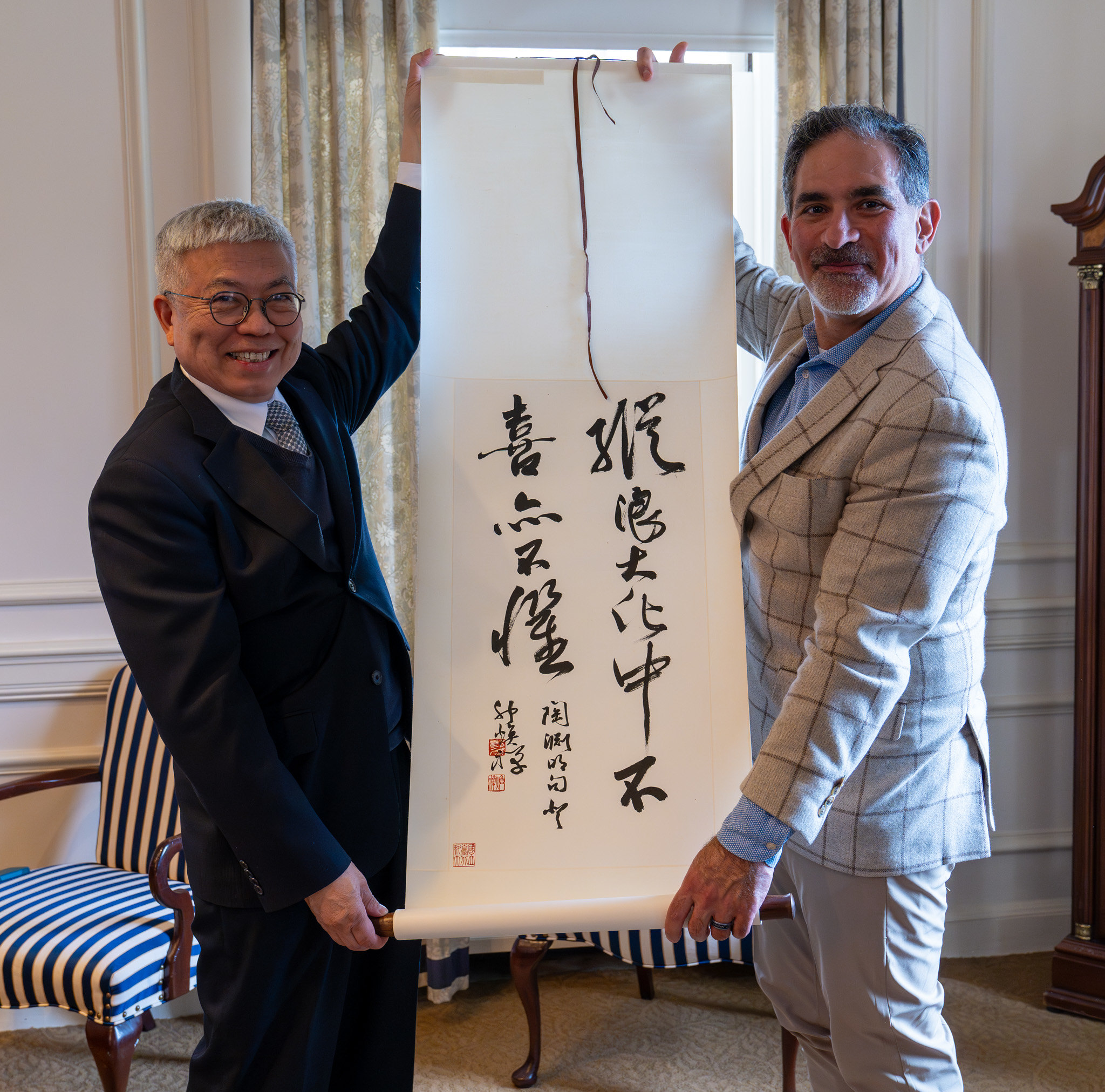 Two men holding a scroll of Chinese calligraphy