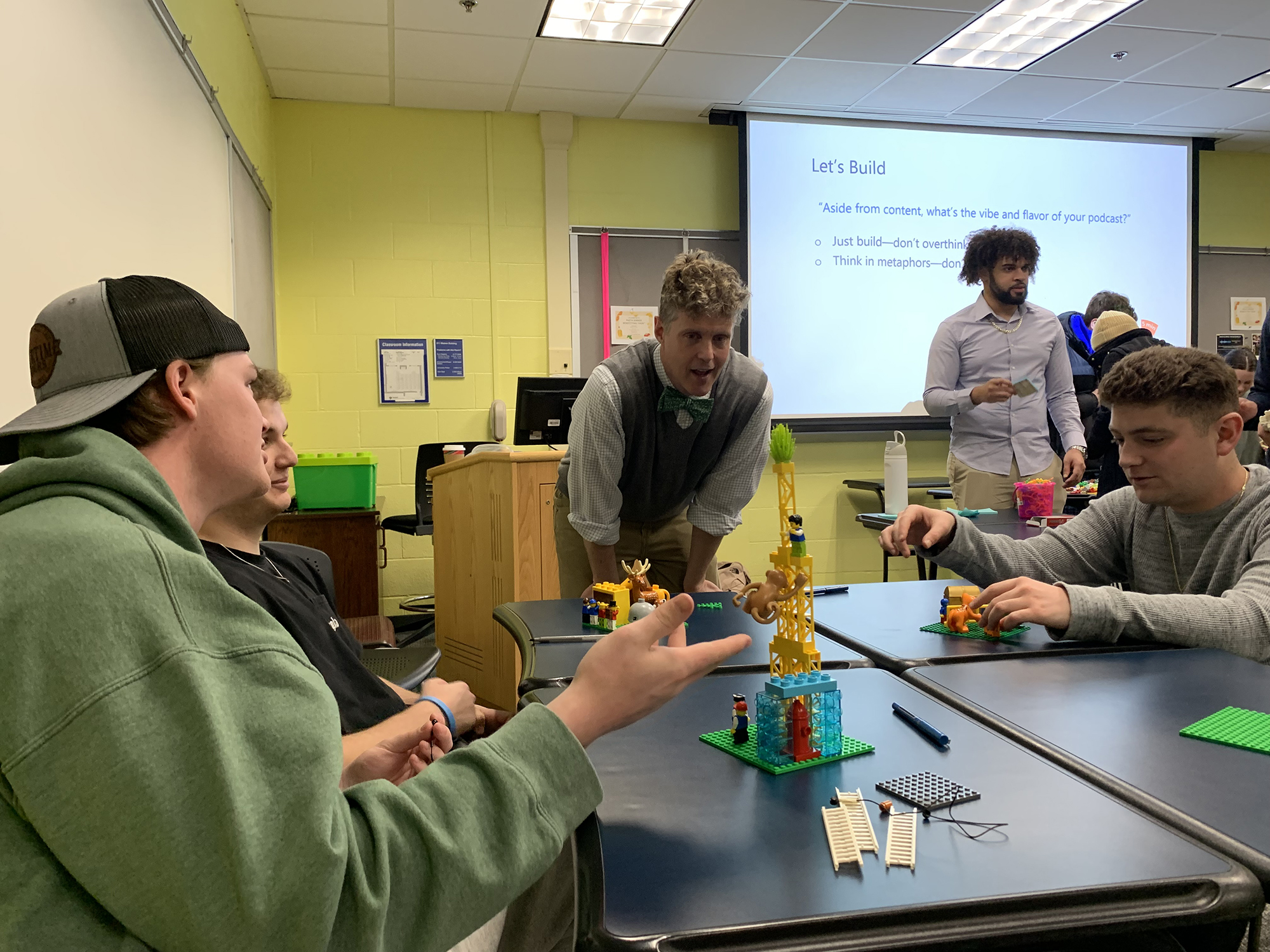 Associate Professor Michael Tews stands next to table of students creating structures with Lego blocks