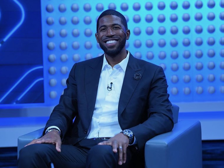 William Dexter Fowler sits on an armchair wearing a suit and smiling at the camera in a blue room.