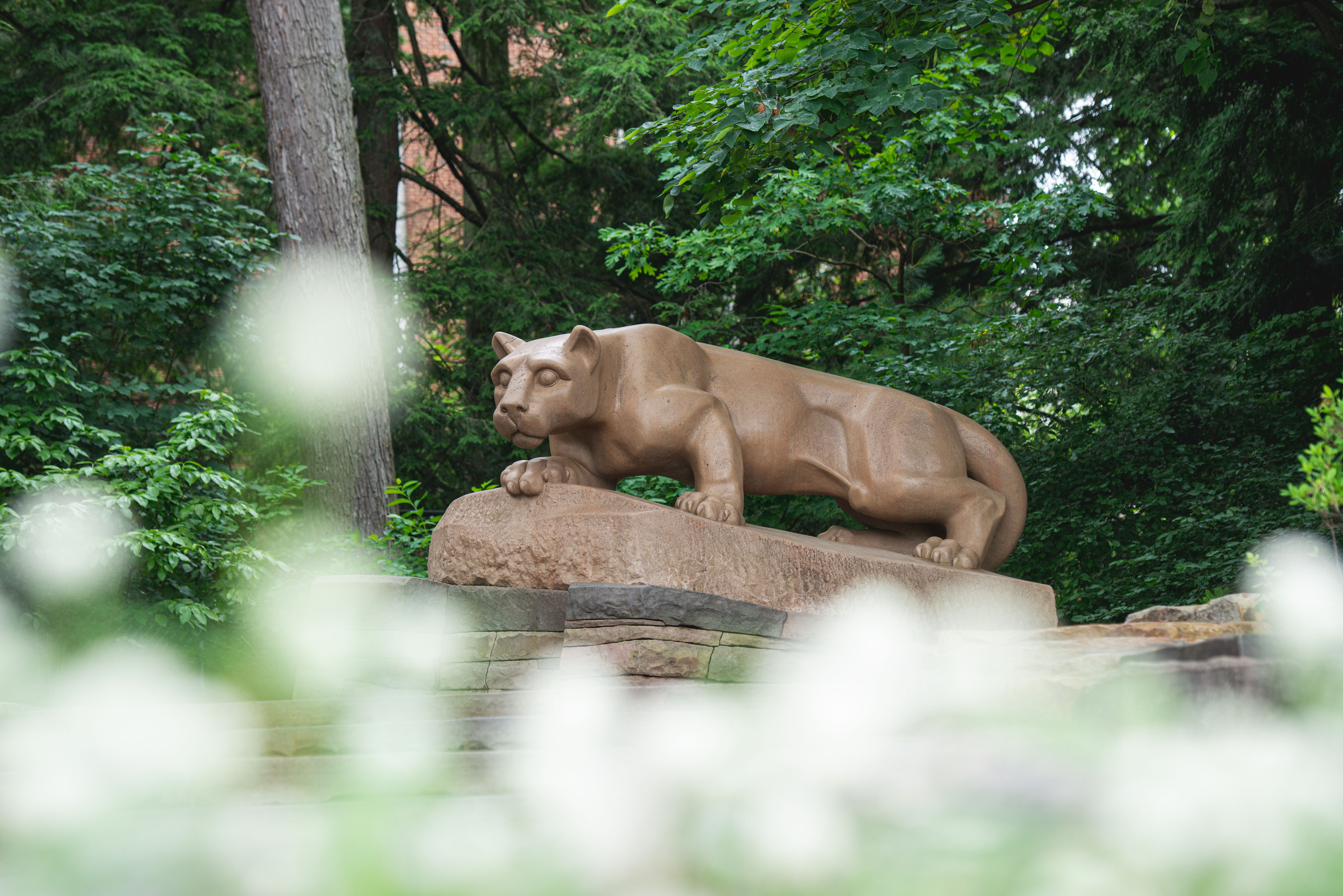 The Penn State Nittany Lion Shrine is shown in focus behind spring flowers in 2019.