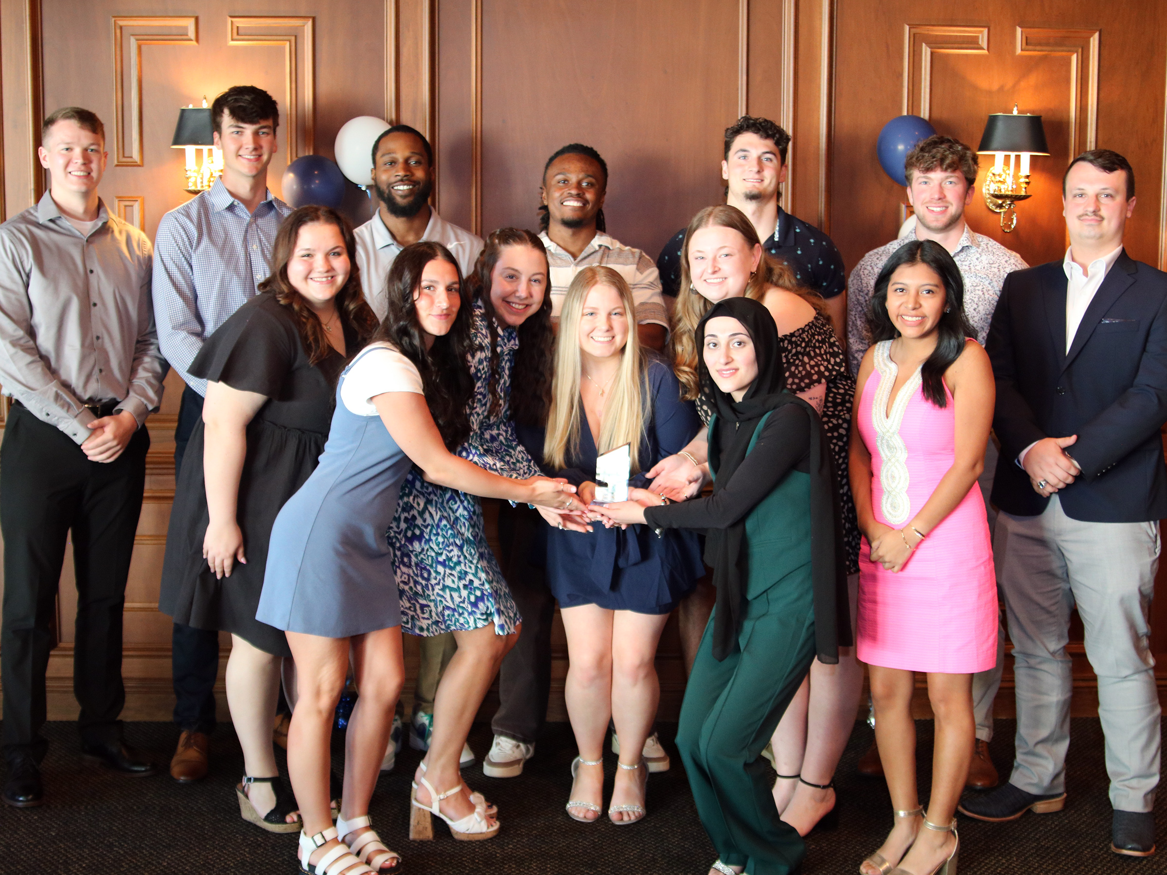 Group of students pose for photo holding an award