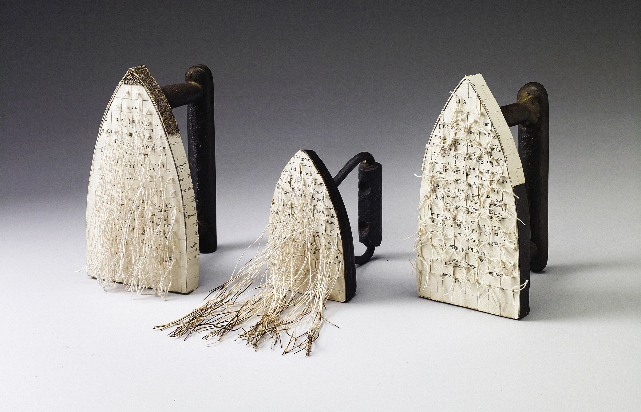 Three antique irons covered in paper, as depicted by artist Carole Kunstadt.