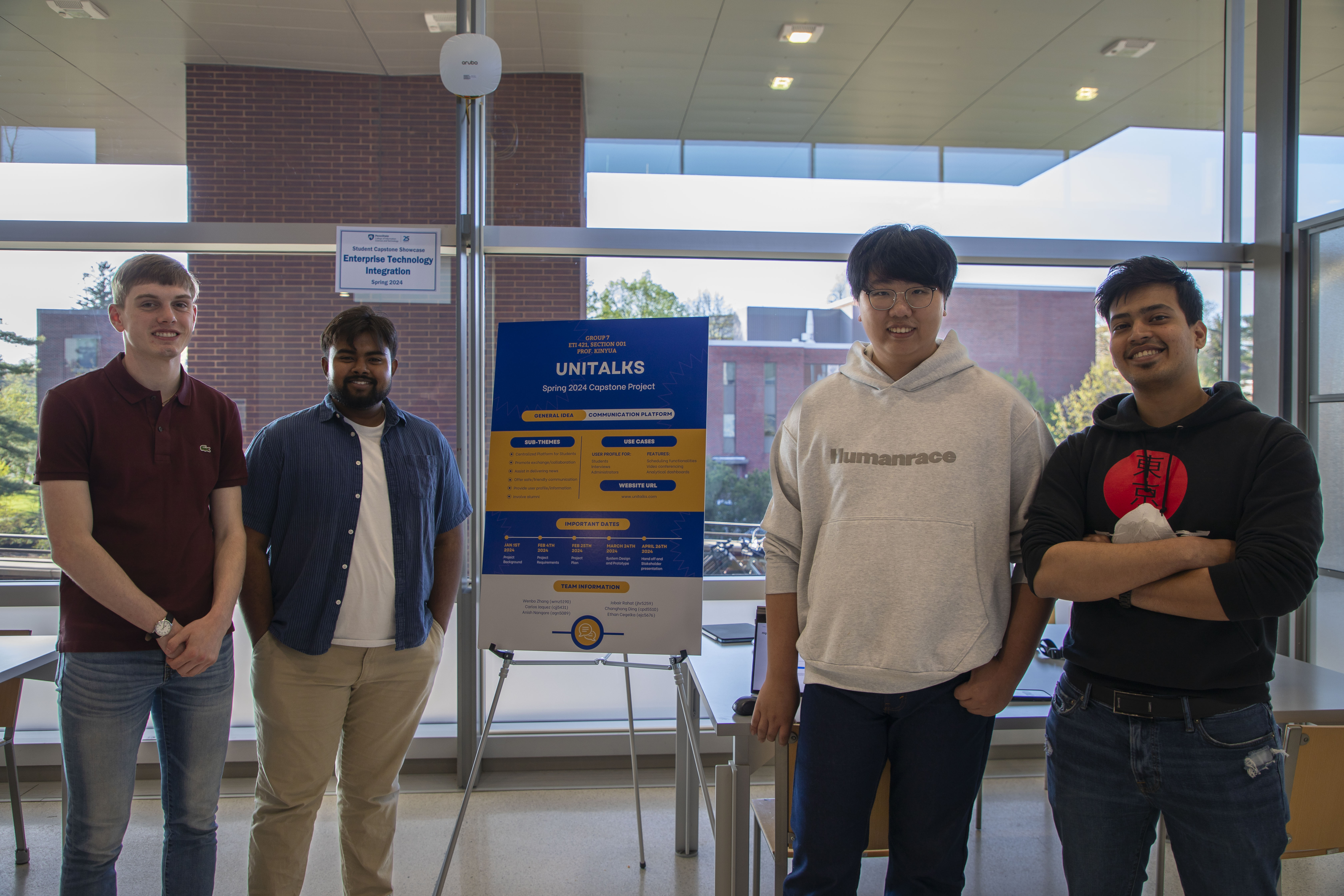 group of four smiling people pose next to academic poster