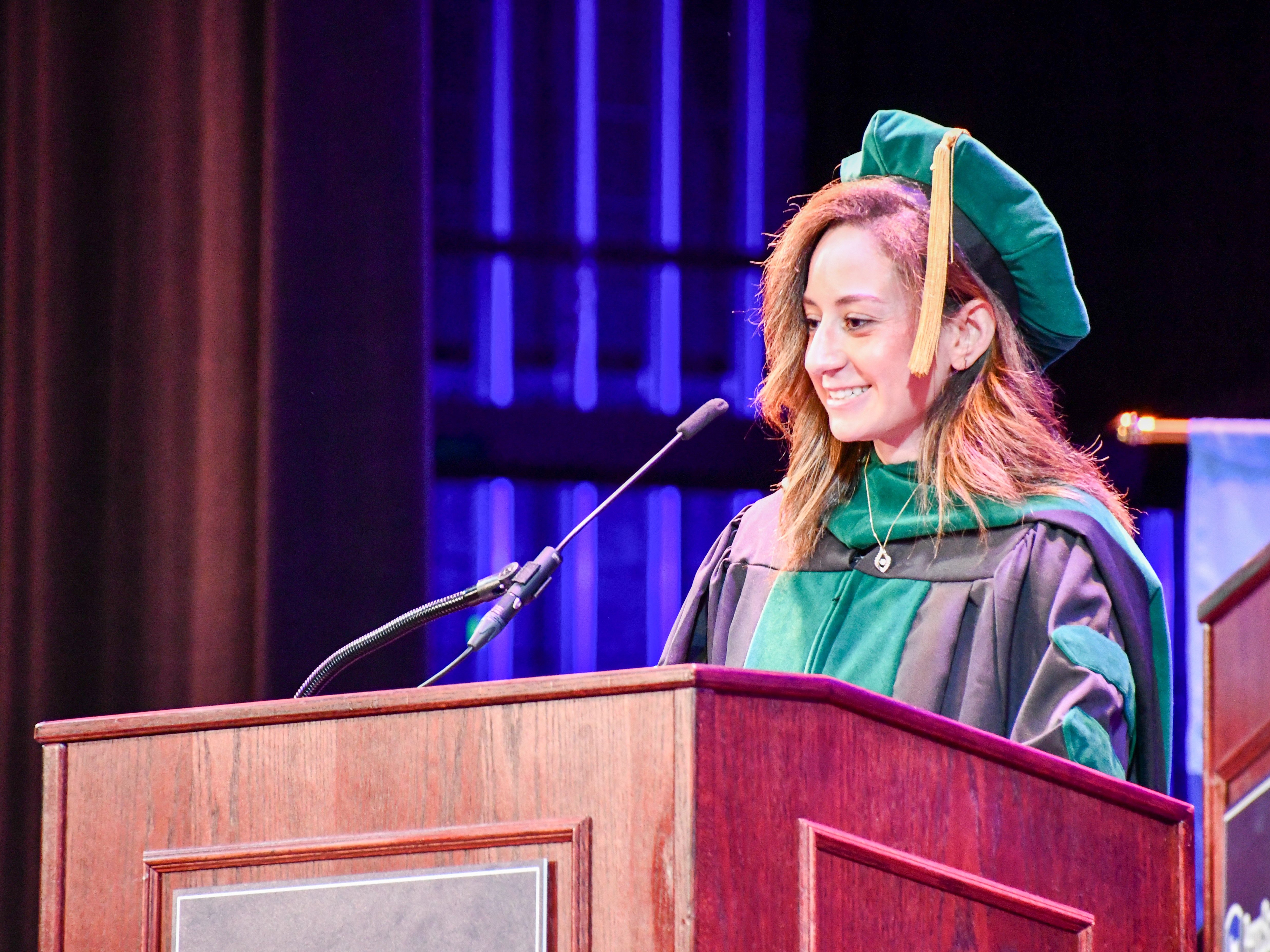 Woman in regalia speaks at a podium.