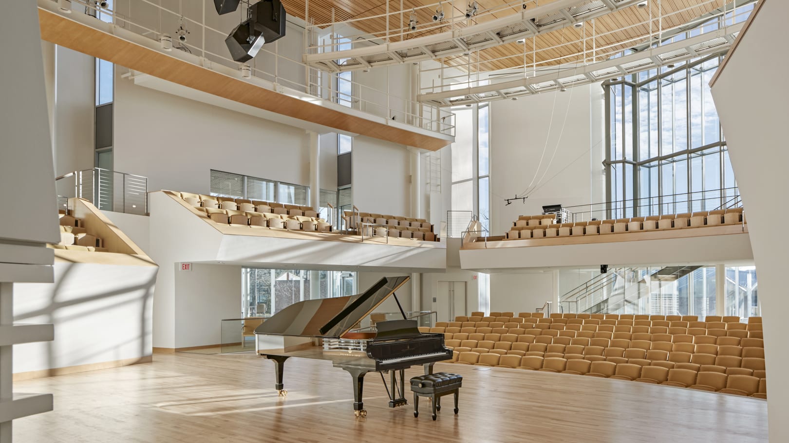 Interior of a recital hall with a grand piano at center stage.