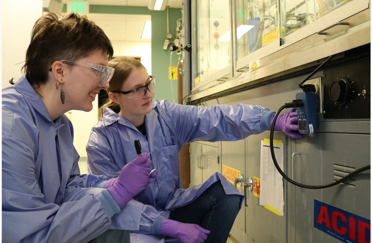 Two students in lab coats and goggles