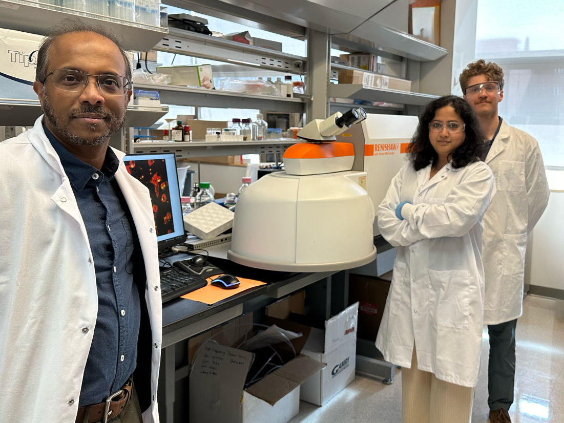 Three people posing in a science lab, two men and one woman