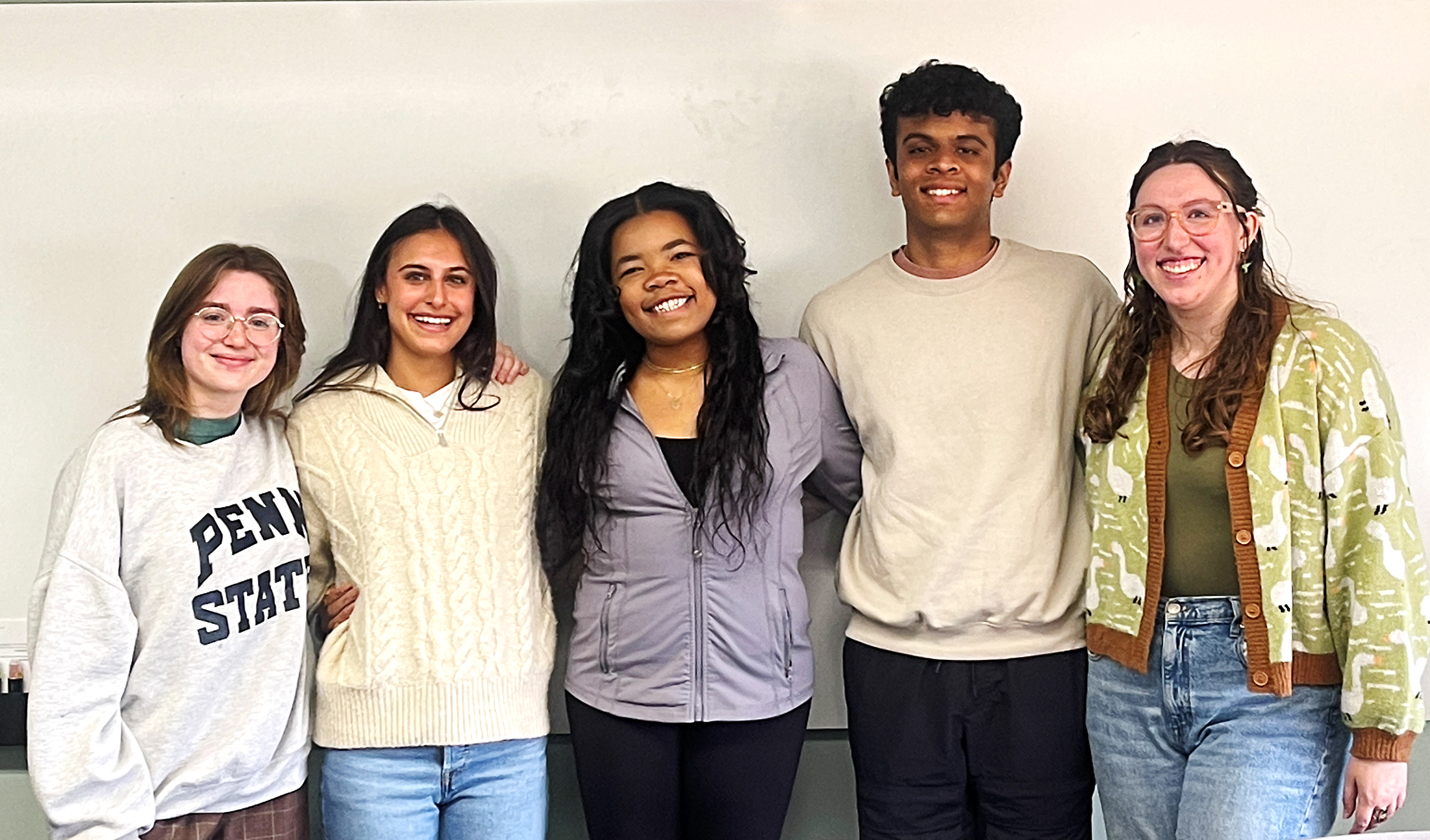 Five people face the camera and smile