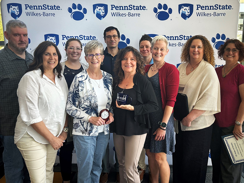 A group of people standing against a backdrop with the Penn State Wilkes-Barre logo.