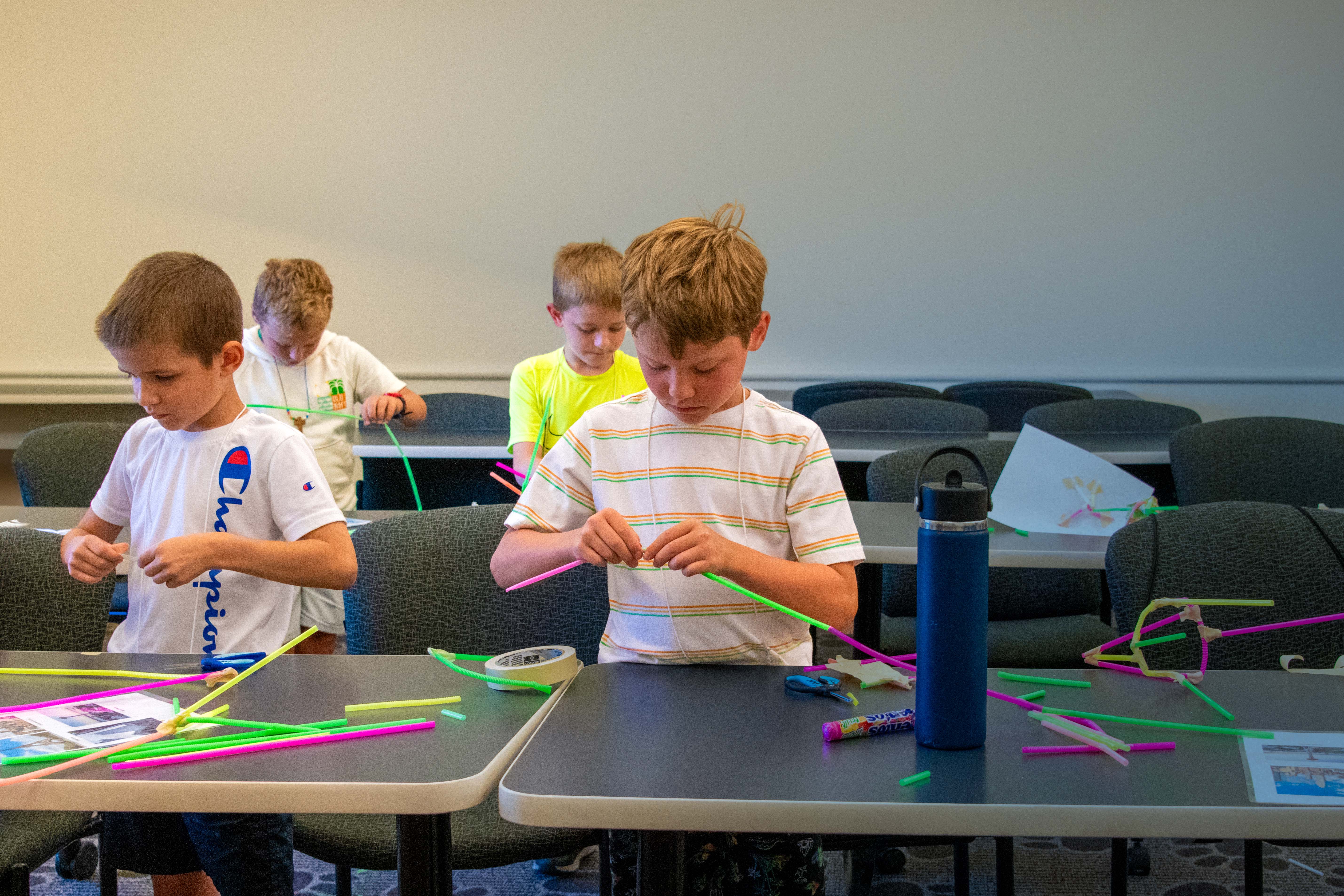 Four children practice arts and crafts inside a classroom.