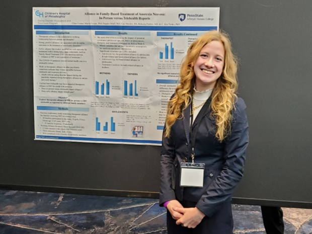 Chloe Connor stands in front of a research poster as an undergraduate student at Penn State.