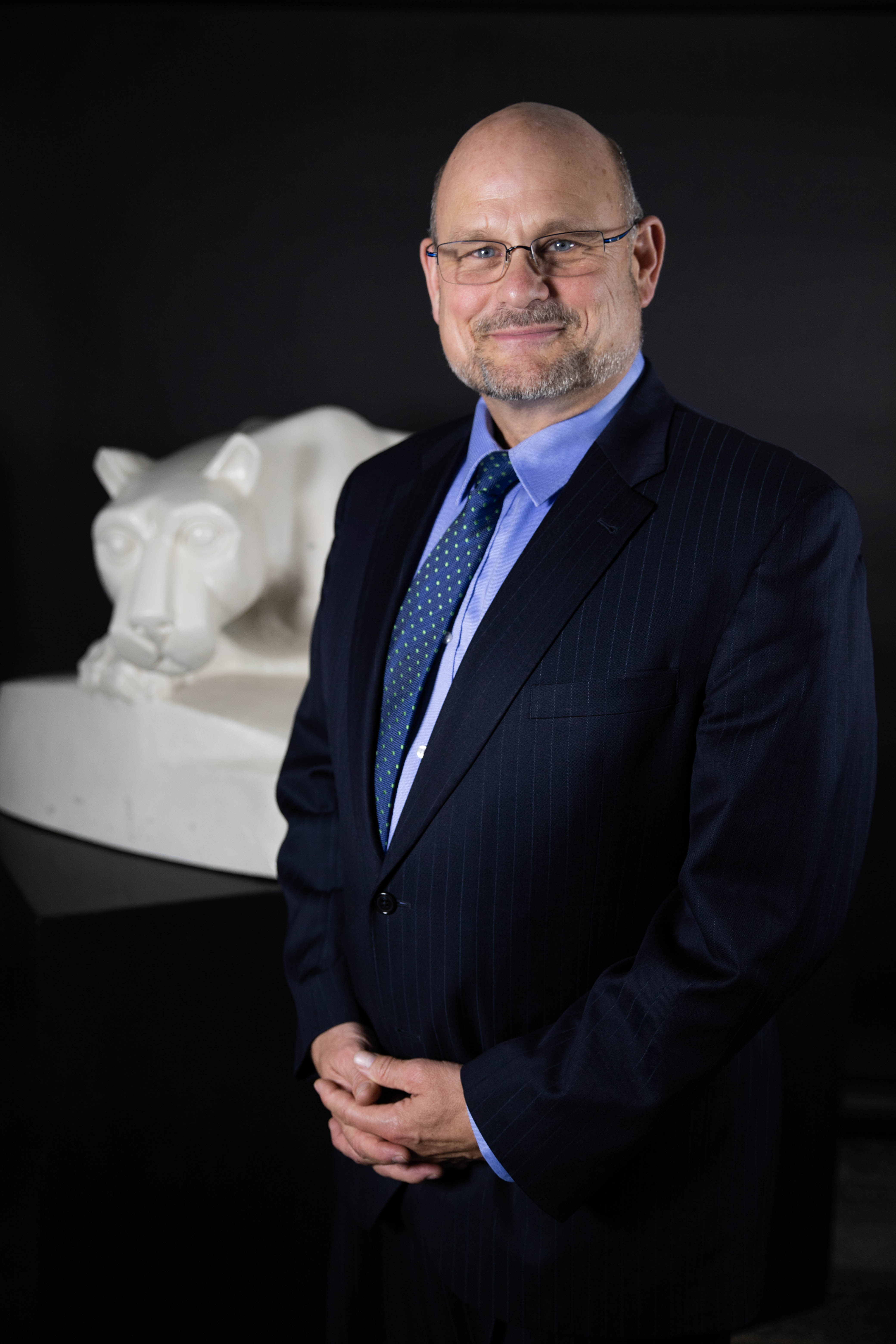 Kevin Snider, chancellor, stands in front of lion shrine statue