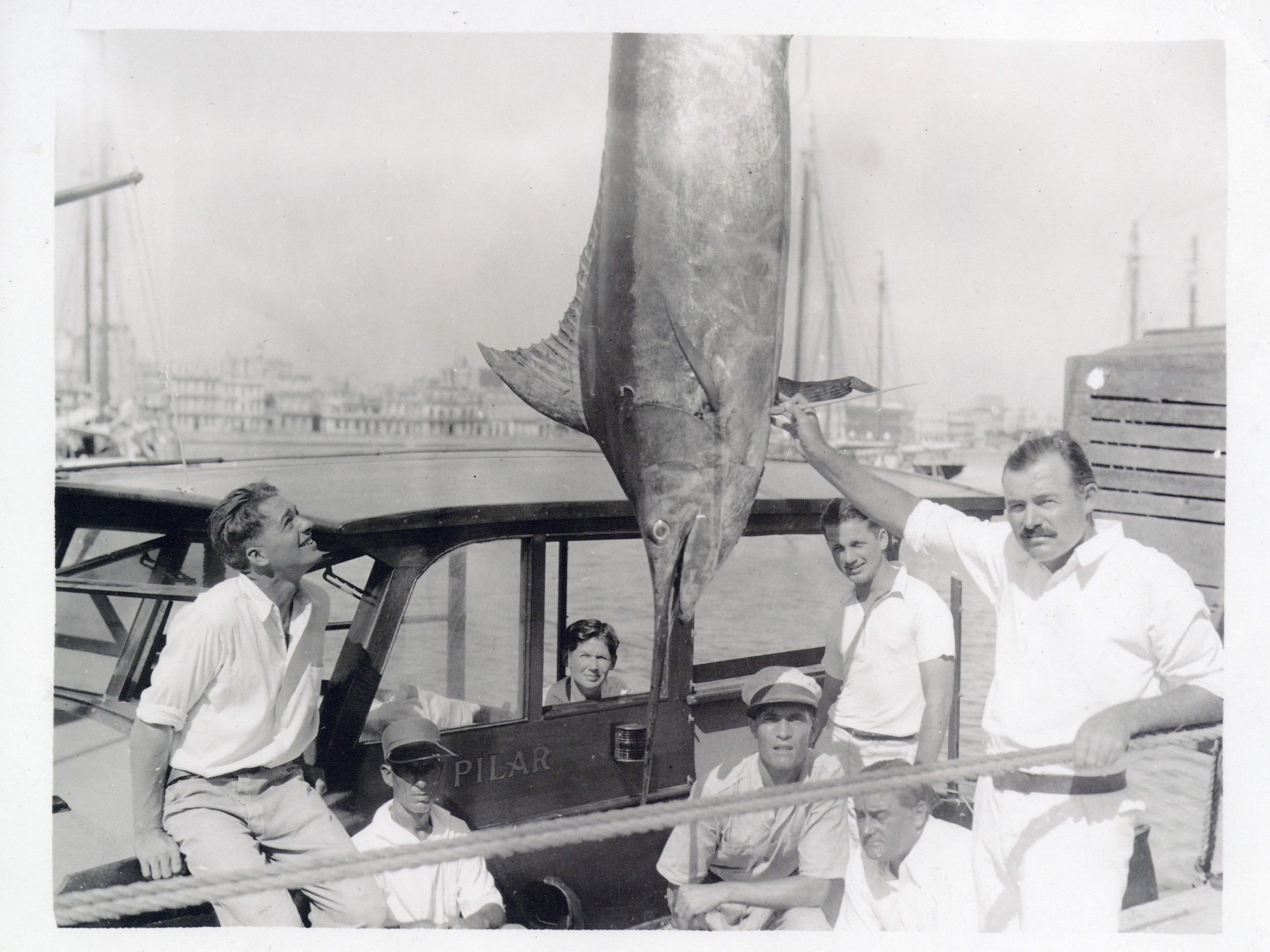 Picture of people on a boat admiring a large fish. 