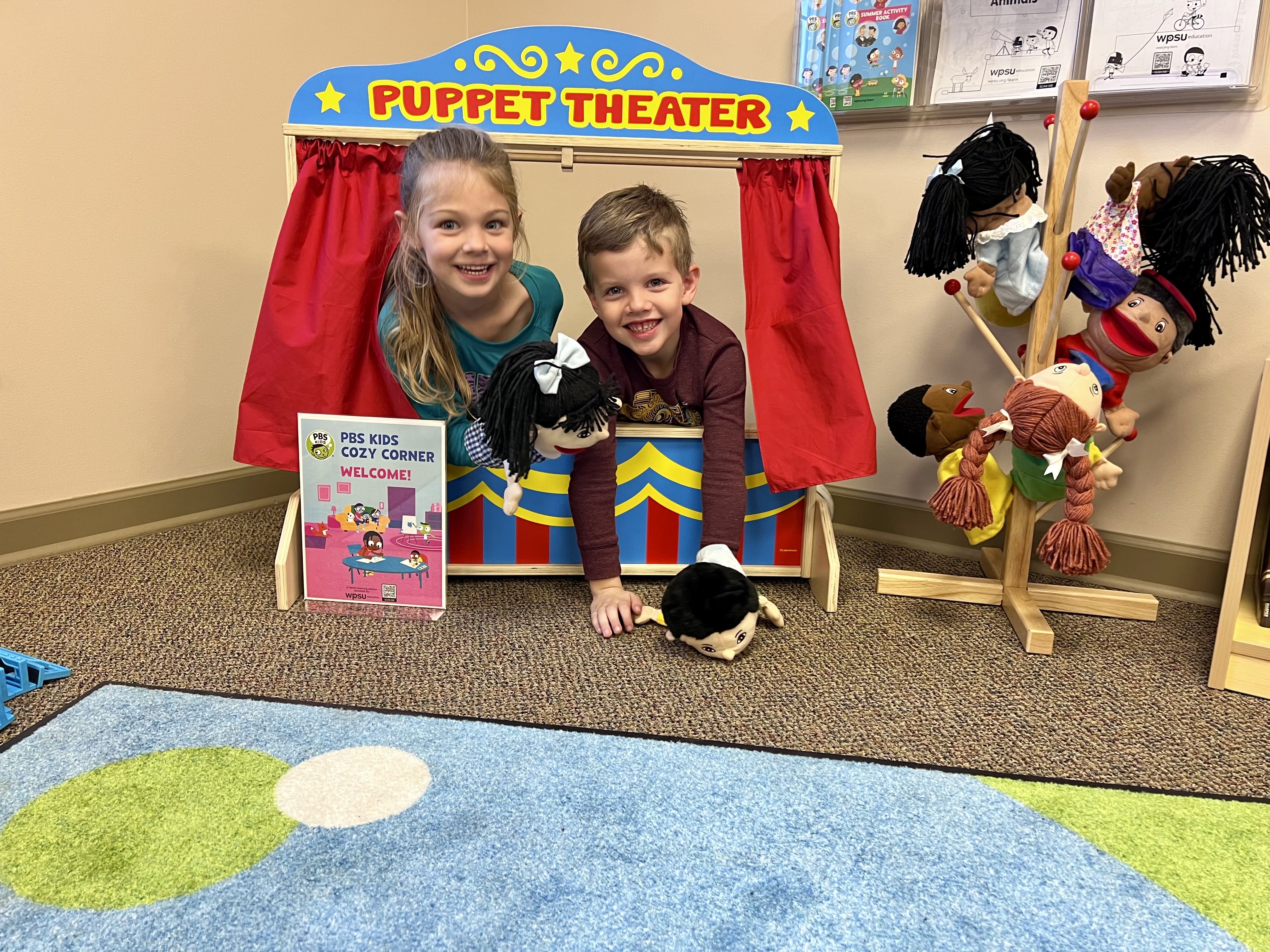 Two kids smiling with puppets