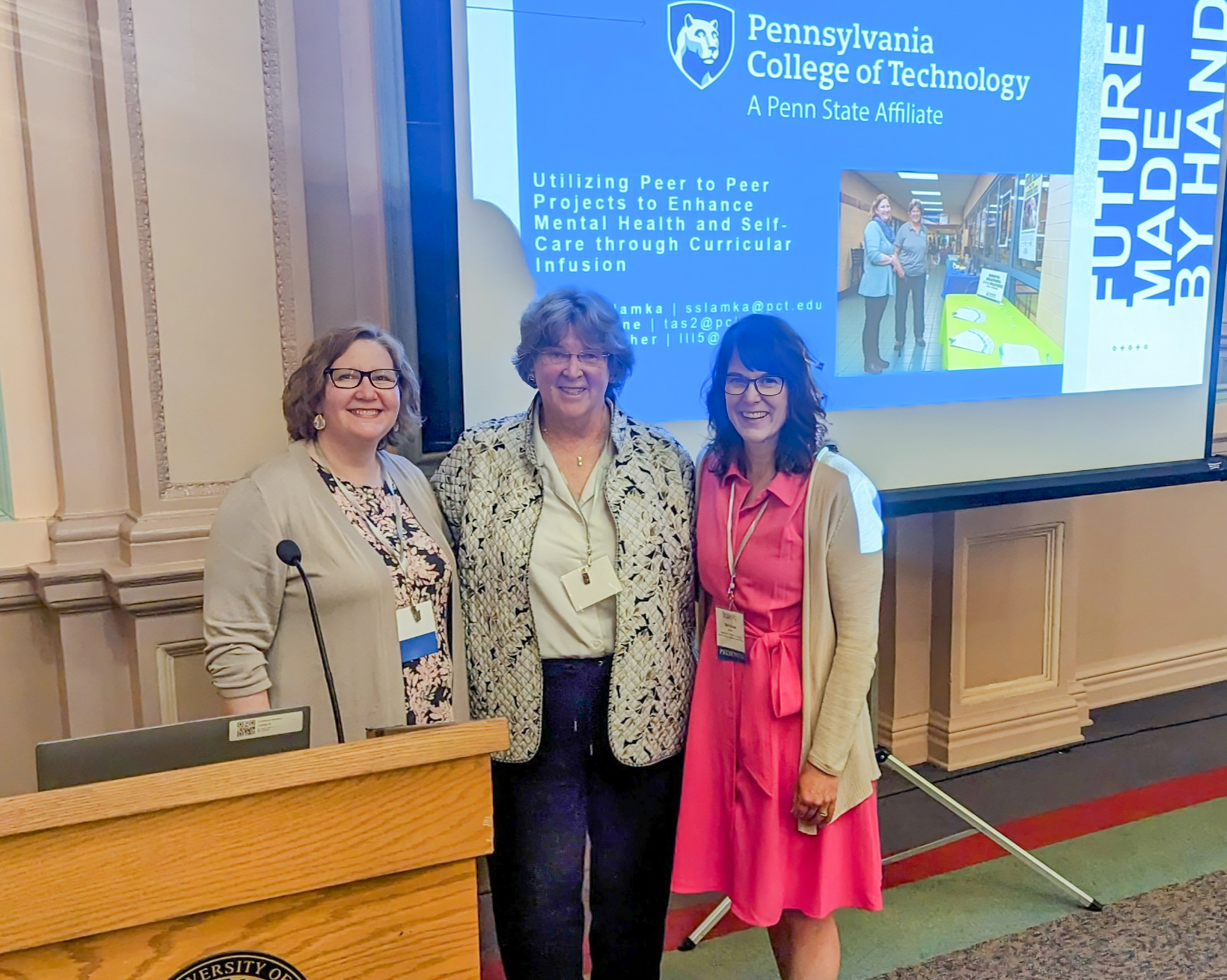 A trio of people pose for a photo in a conference center meeting room