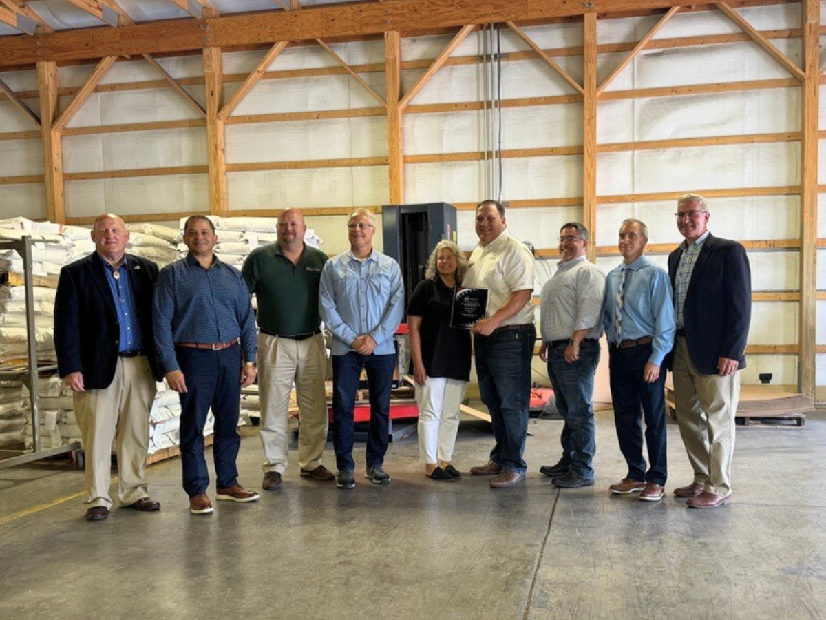 Nine individuals, including state officials and the award recipient, pose for a photo