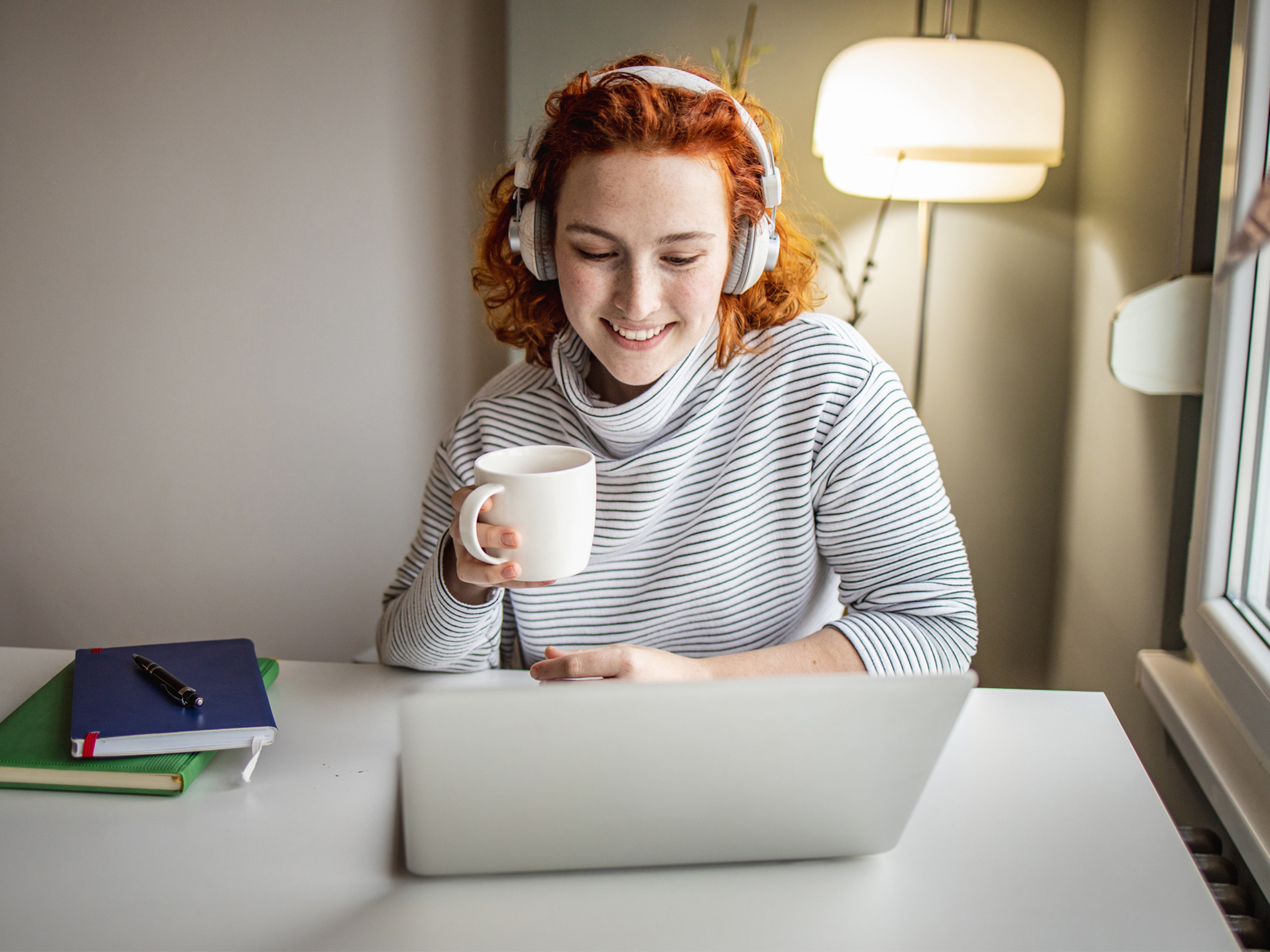 Person using a laptop and wireless headphones while working at home