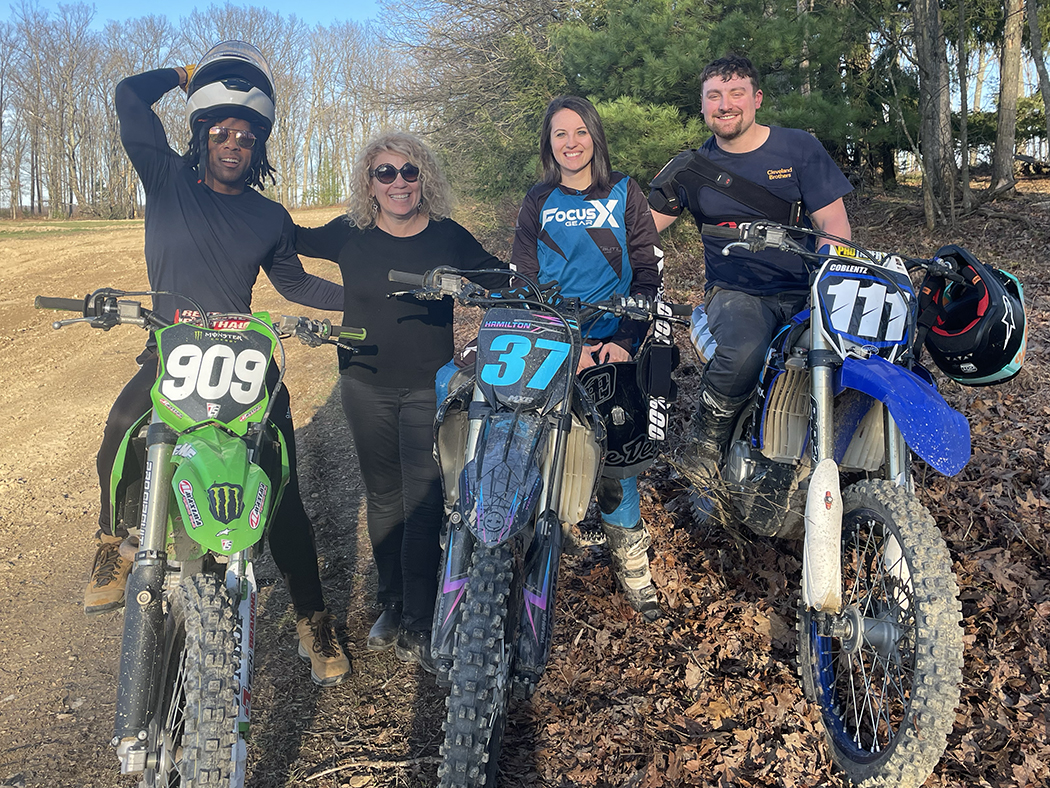 Four people with three motocross bikes