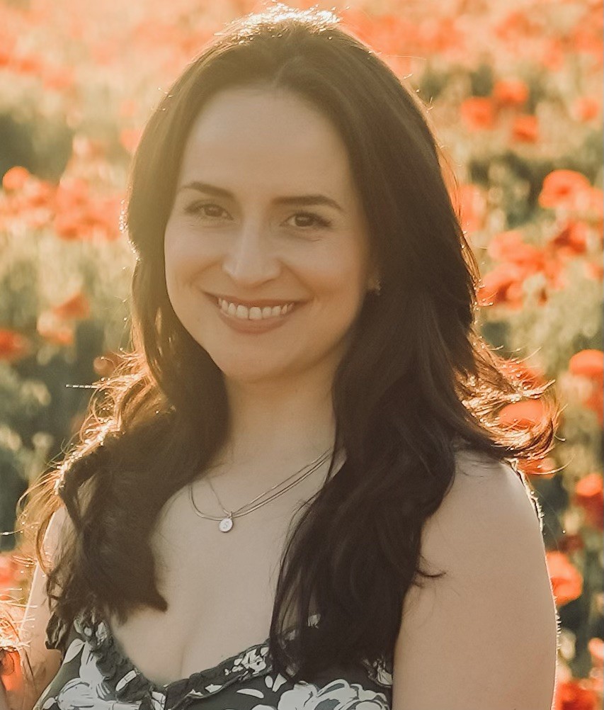 Latina with dark hair and a sun dress smiling in a shaft of sun light