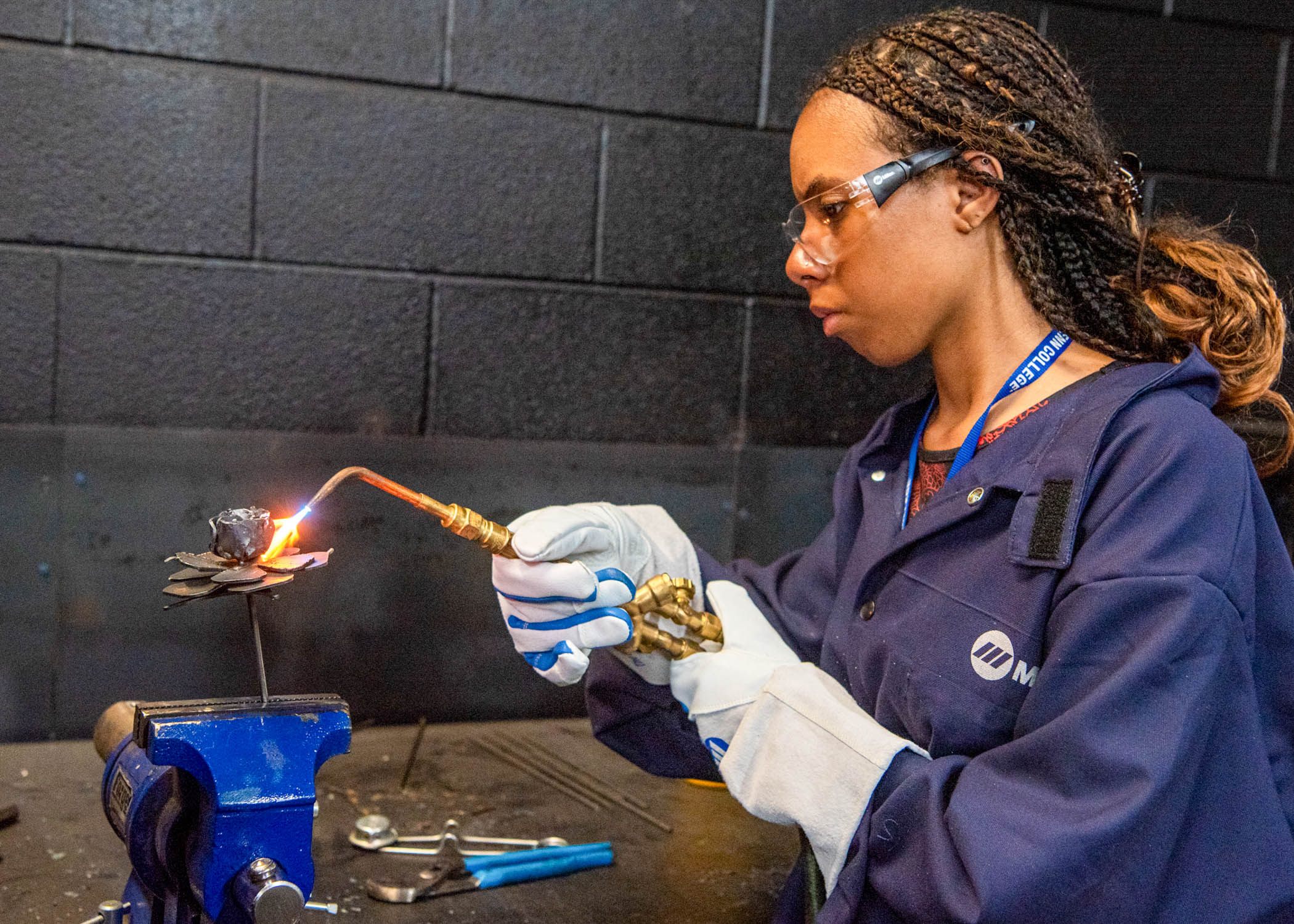 A student wearing protective clothing welds in a class