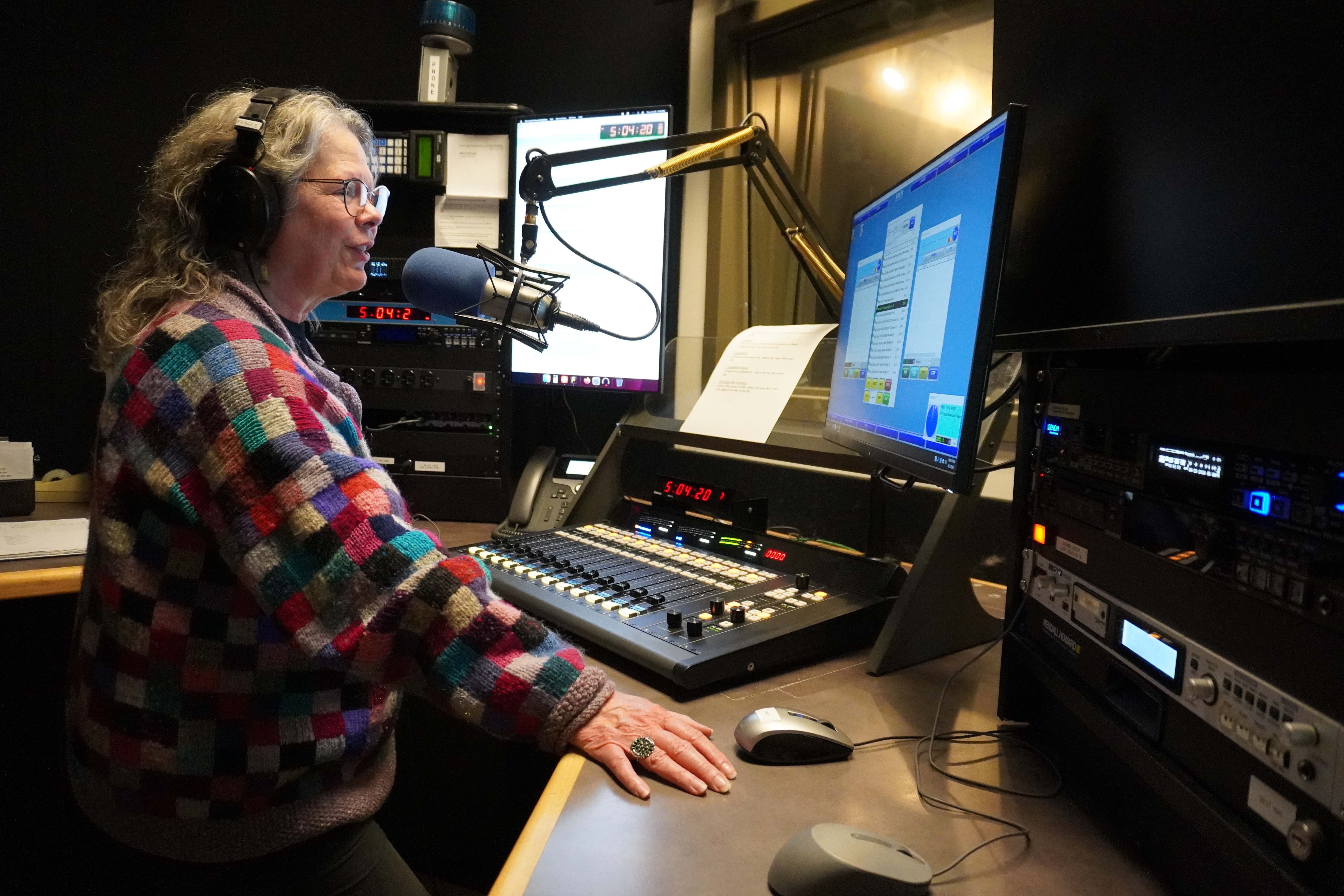 WPSU host in colorful sweater reads copy on air