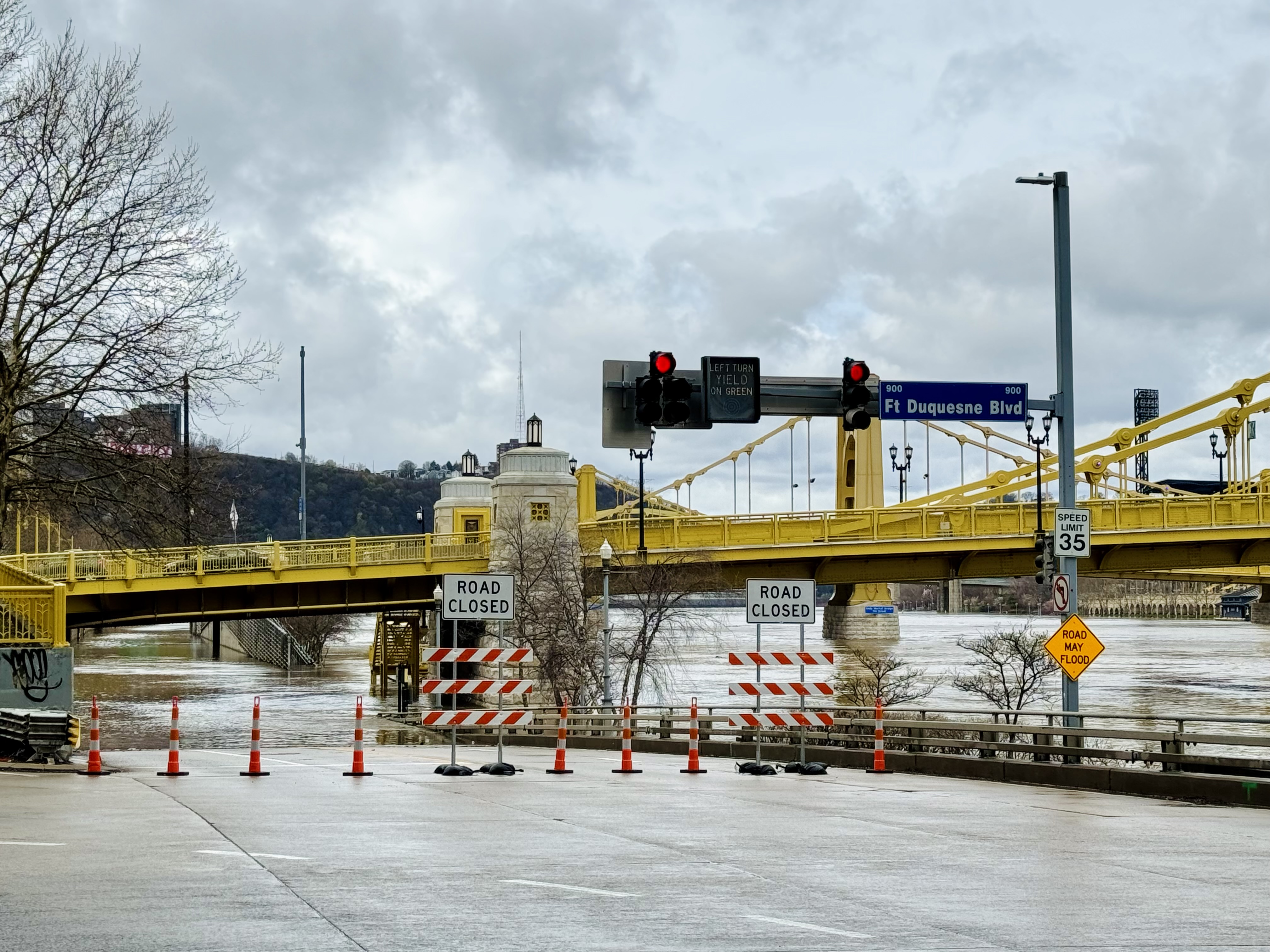 Yellow metal bridge, flooding across roadway, road block signs, red traffic lights