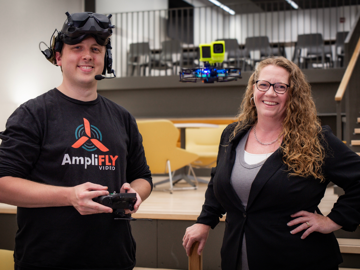 Kate Myers and Tyler Henderson pose for a photo with their drone hovering between them