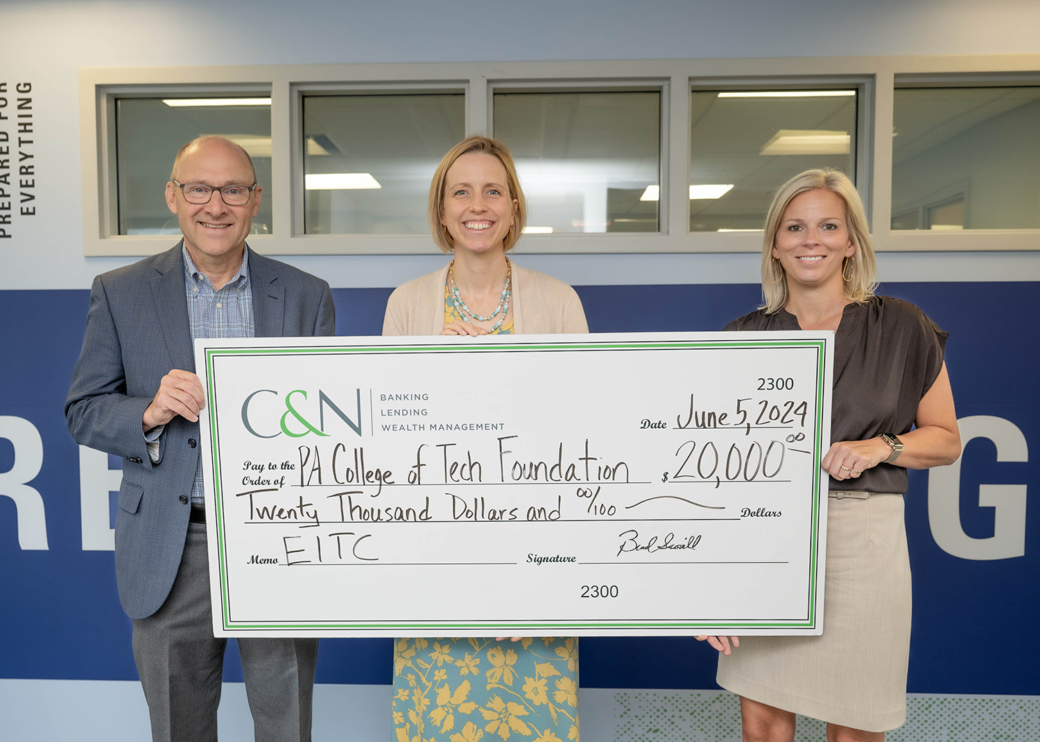 Three people hold up a giant check