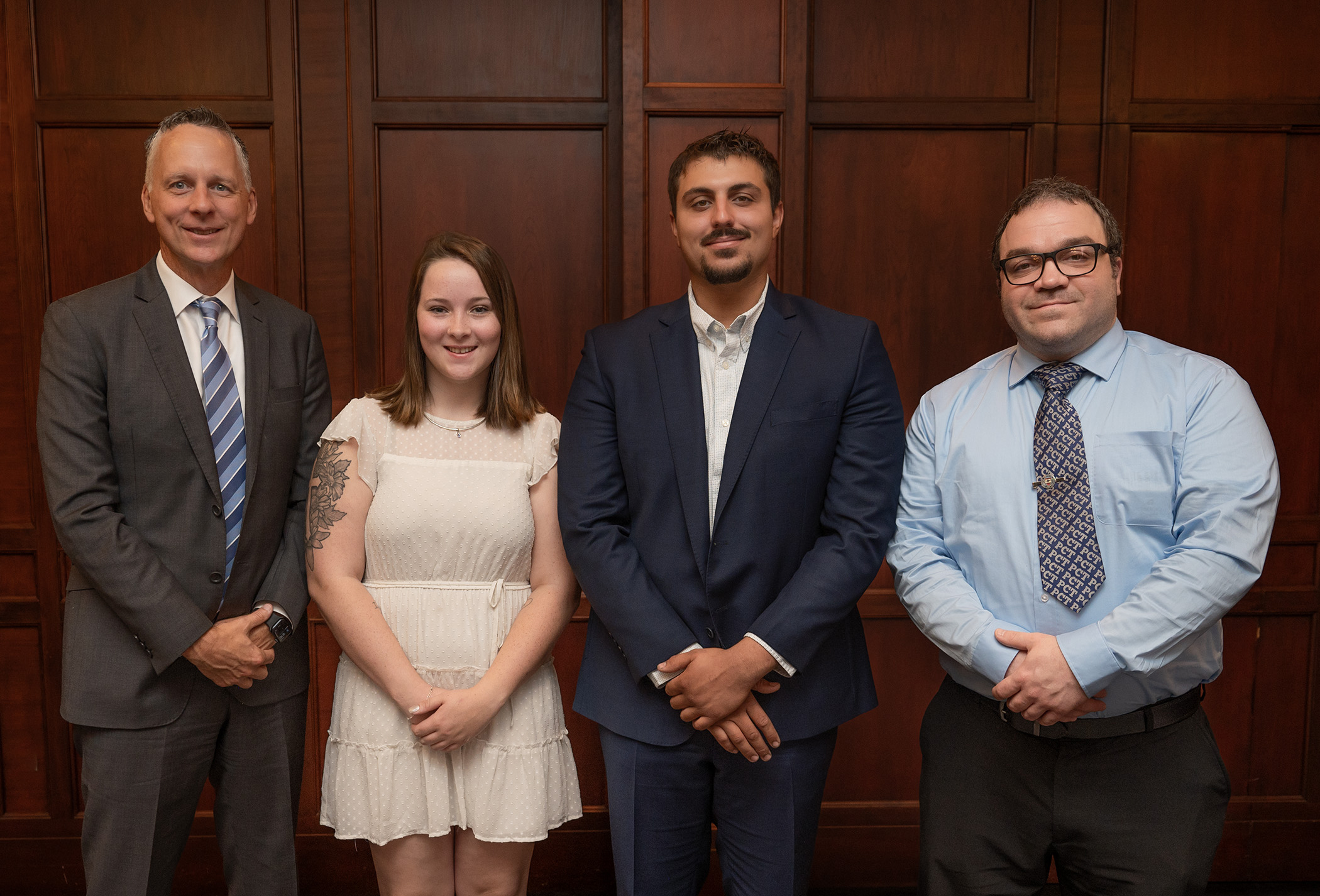 Four people dressed in business casual pose for a photo.