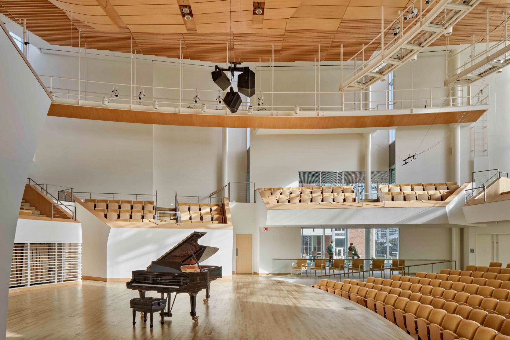 A spacious hall with seats and a single grand piano on the stage