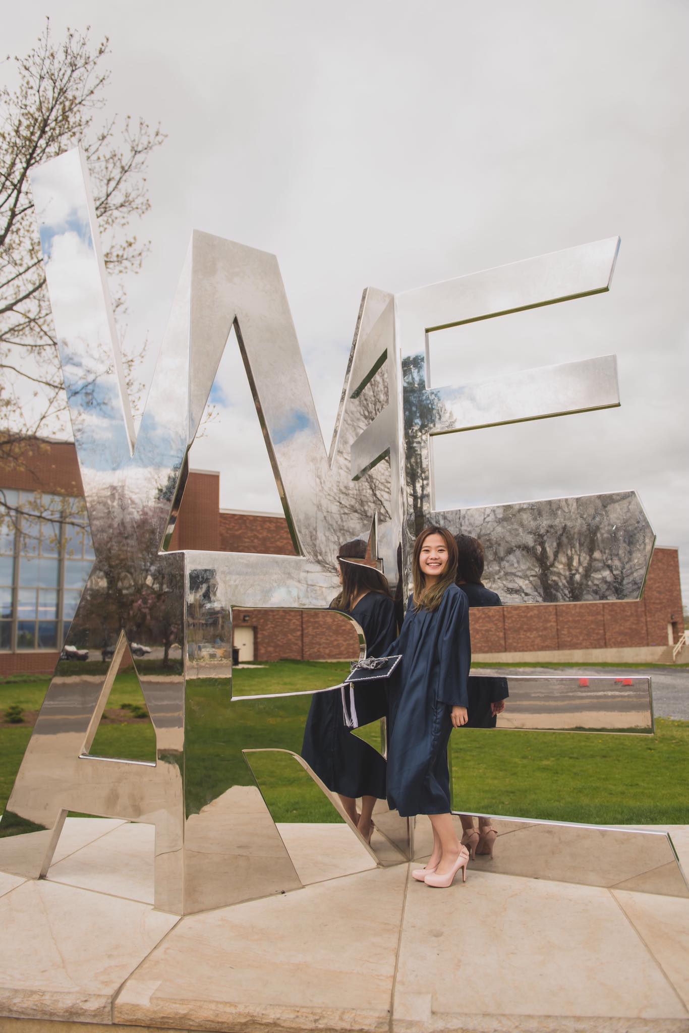 A young woman in front of a mirror statue in the shape of We Are