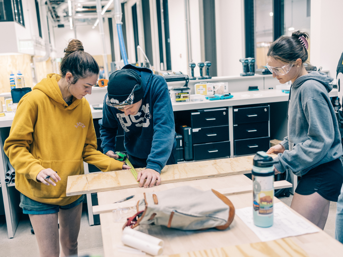 Three students making measurements on a wooden board in OriginLabs