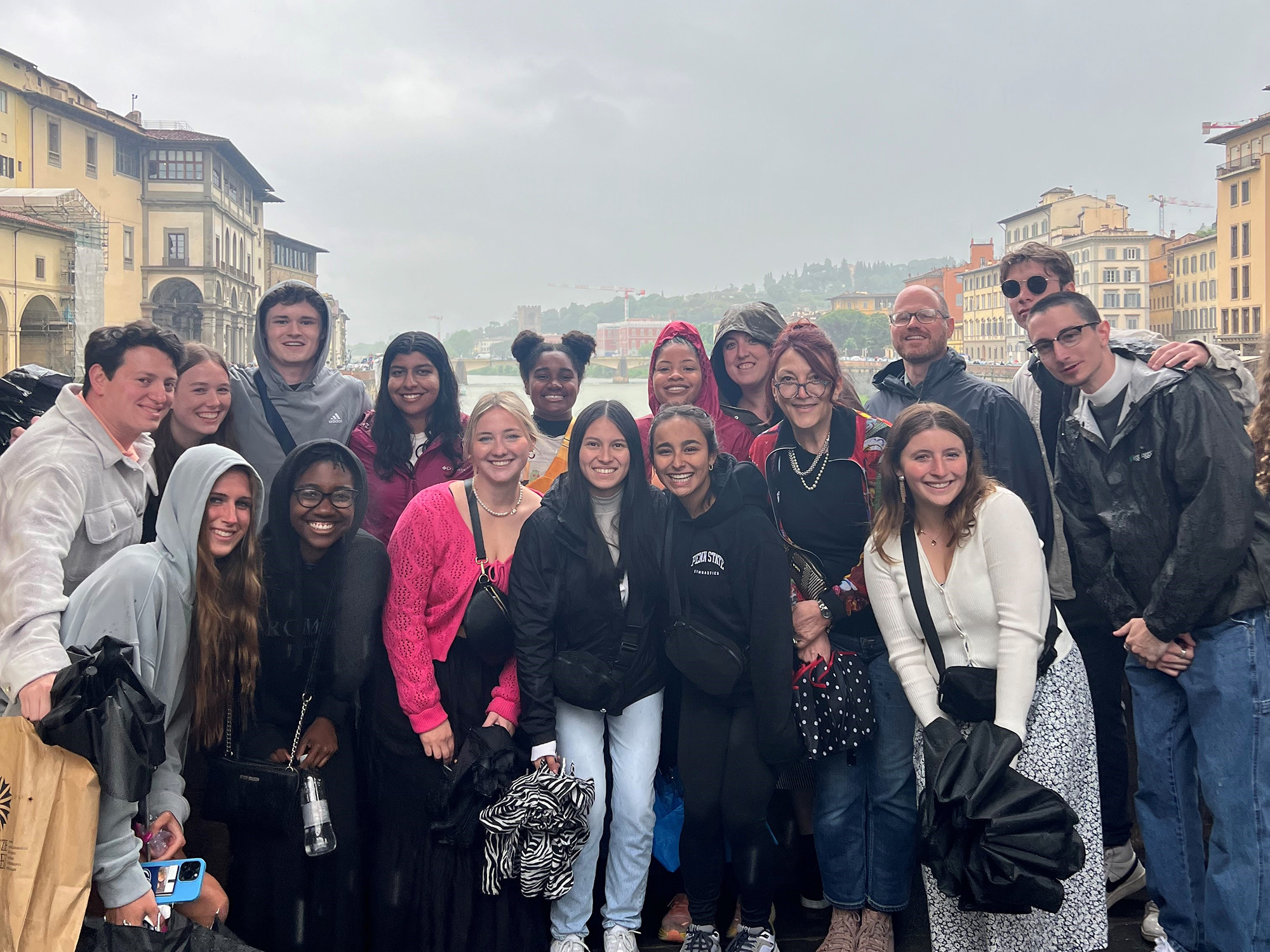 Students in raincoats gather on the Ponte Vecchio bridge in Florence, Italy