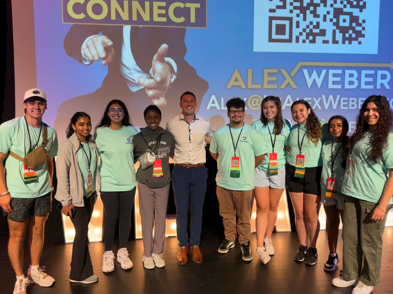 students smiling on a stage inside an auditorium 