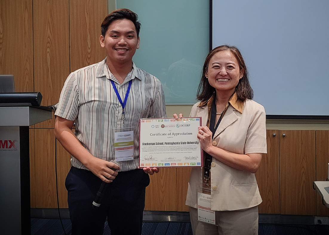 Chingwen Cheng at right accepts a certificate from a leader of the Association of Pacific Rim University Sustainable Cities and Landscapes at left.