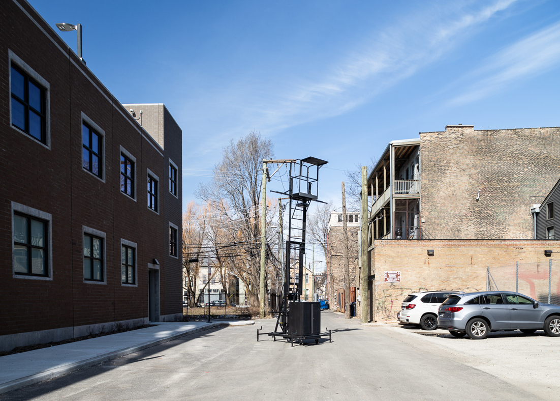 TThe Unmonument installation on a street, which consists of a matte black, steel industrial lift. 