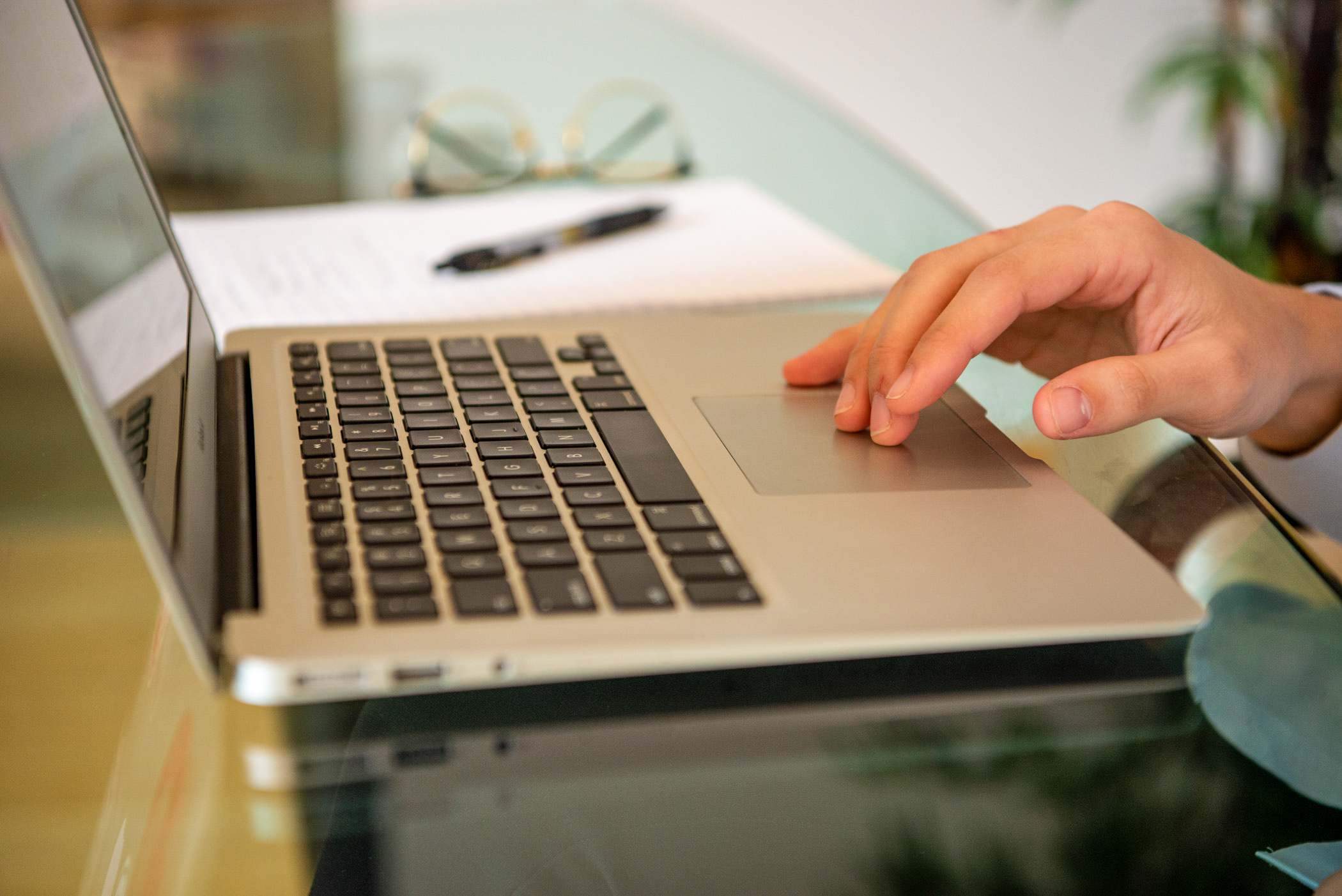 A closeup of a computer keyboard with a hand using the tracking mouse pad.