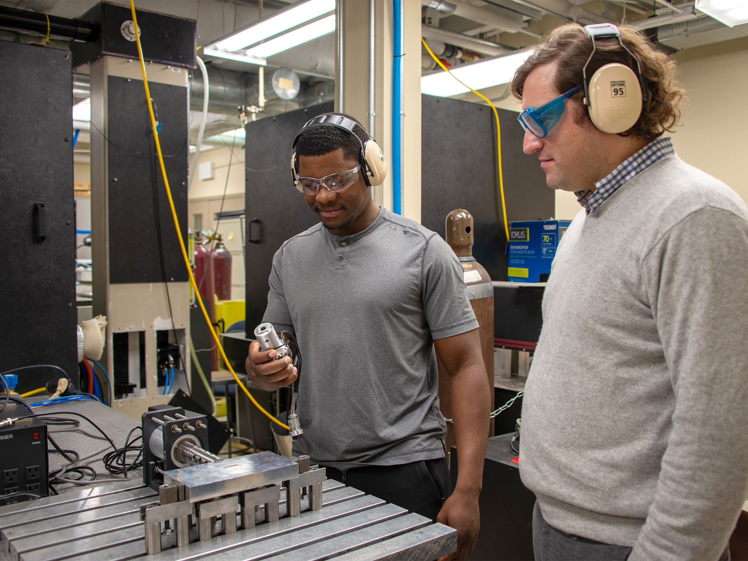 Two individuals look down at a ultrasonic lab setup in a lab setting. 