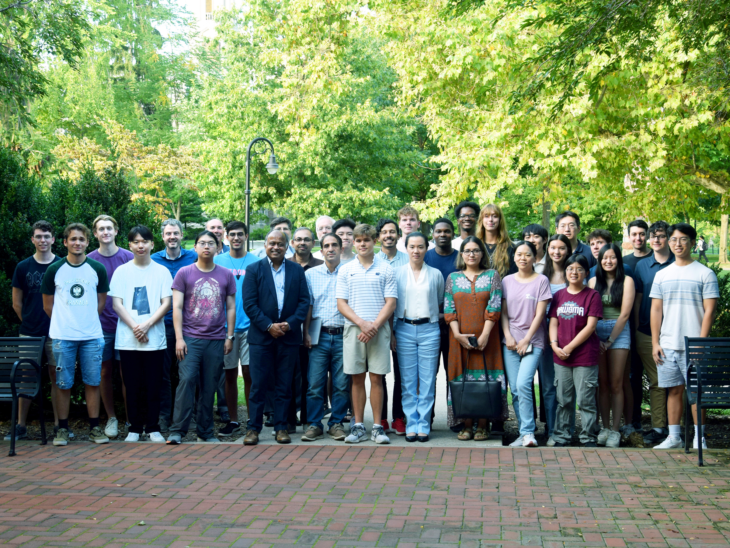 A large group of electrical engineering students and faculty pose outdoors on a brick walkway.