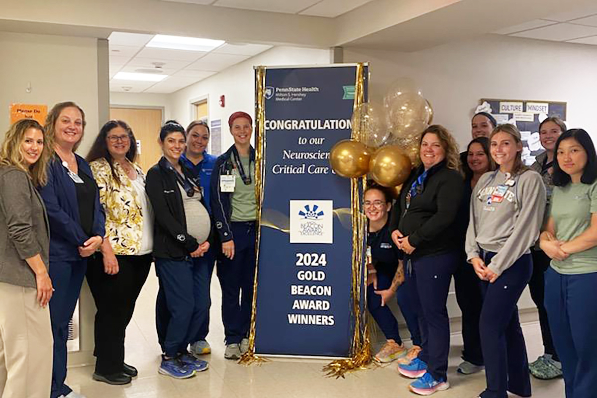 A group of people pose for a photo with a sign touting "2024 Gold Beacon Award Winners."