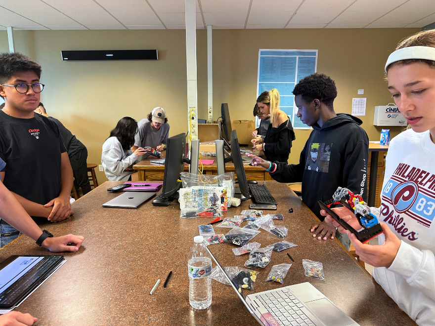 students working with computers and other STEM-related tools at a long desk