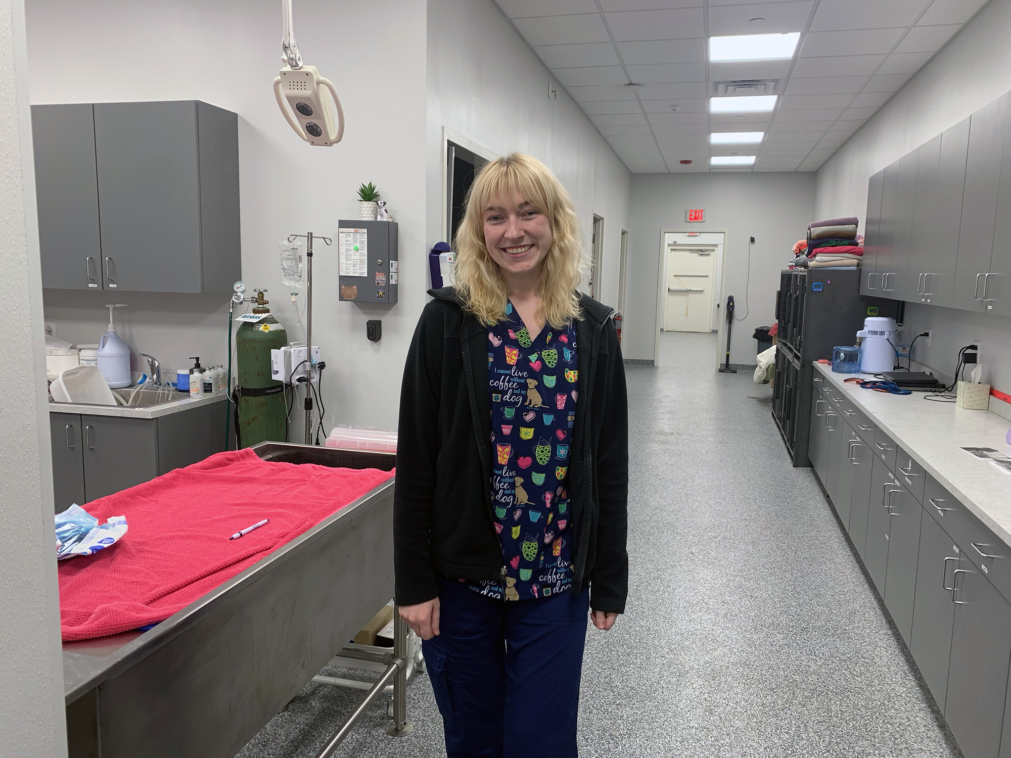 A photo of Cora wearing scrubs in a veterinary office